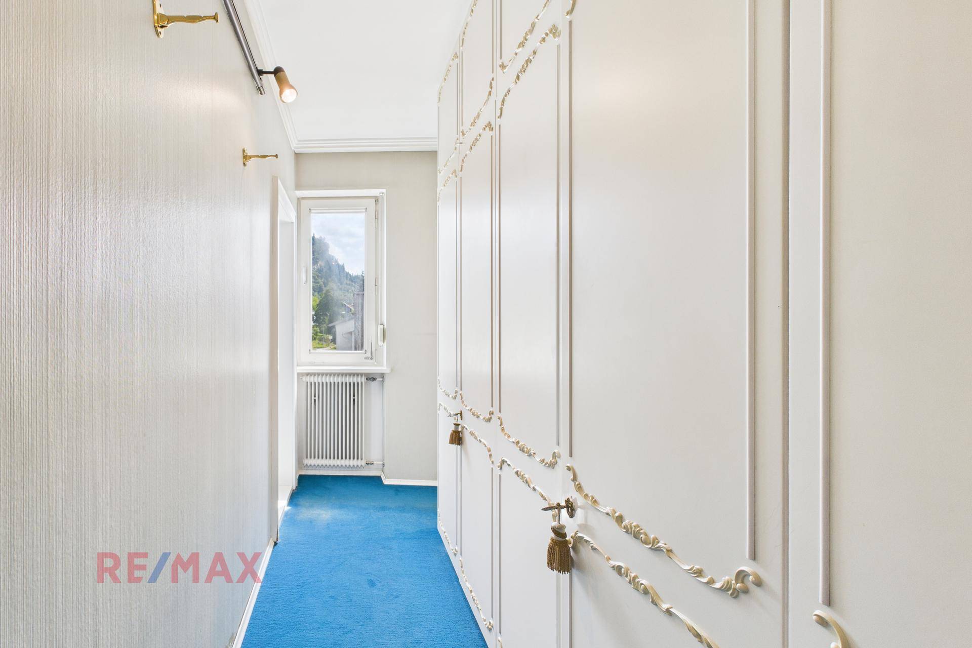 Flur mit blauer Teppichboden und eleganten Einbauschränken.