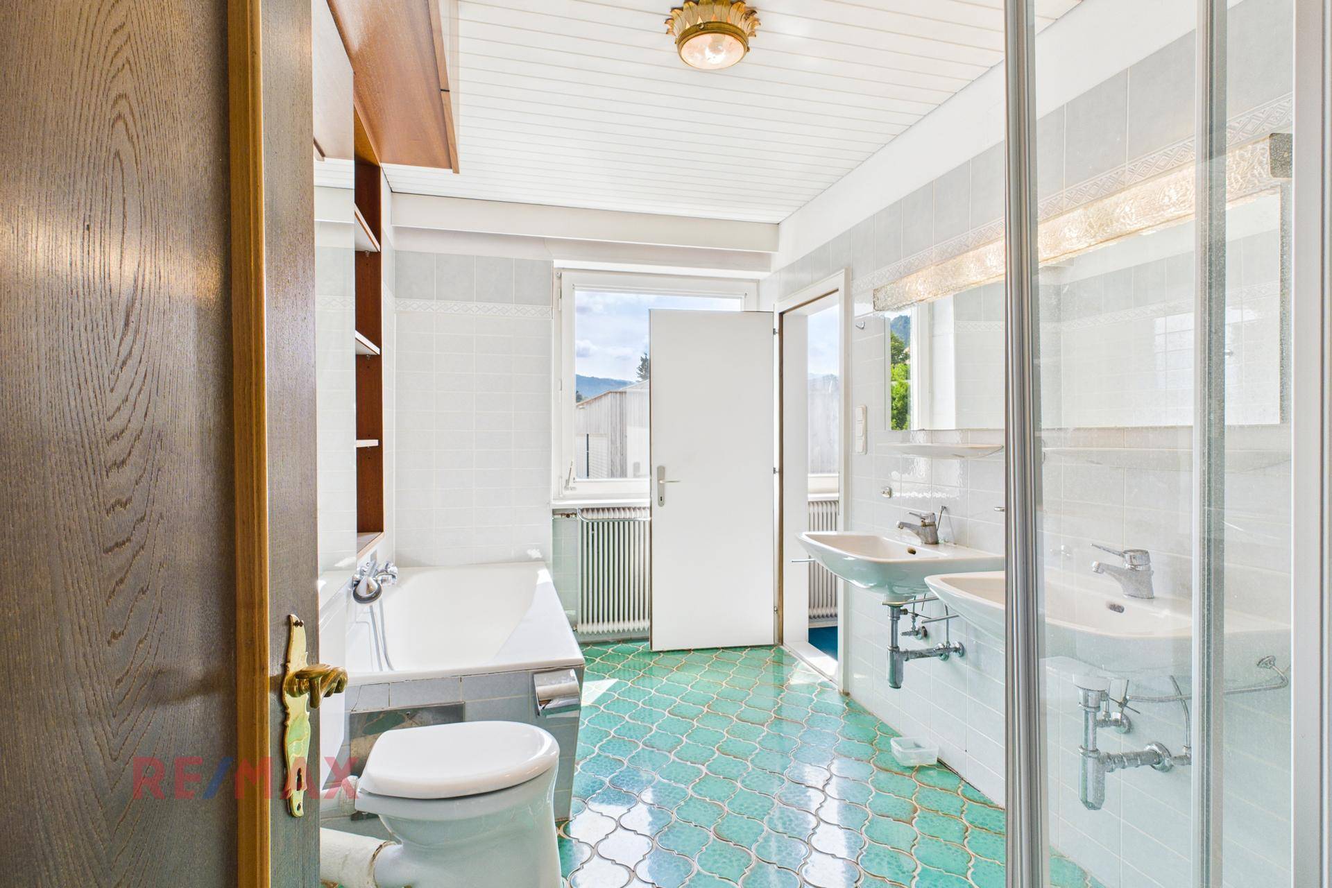 Badezimmer mit Badewanne, Dusche, Doppelwaschbecken und Fenster.