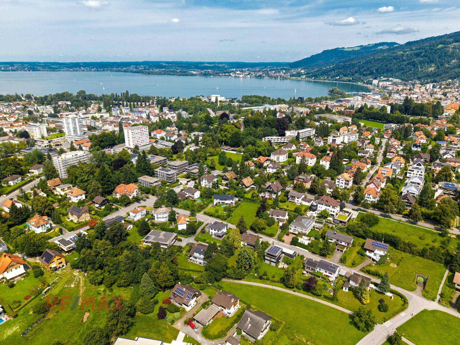 Weitläufige Luftaufnahme der Wohngegend mit See und Bergen im Hintergrund.