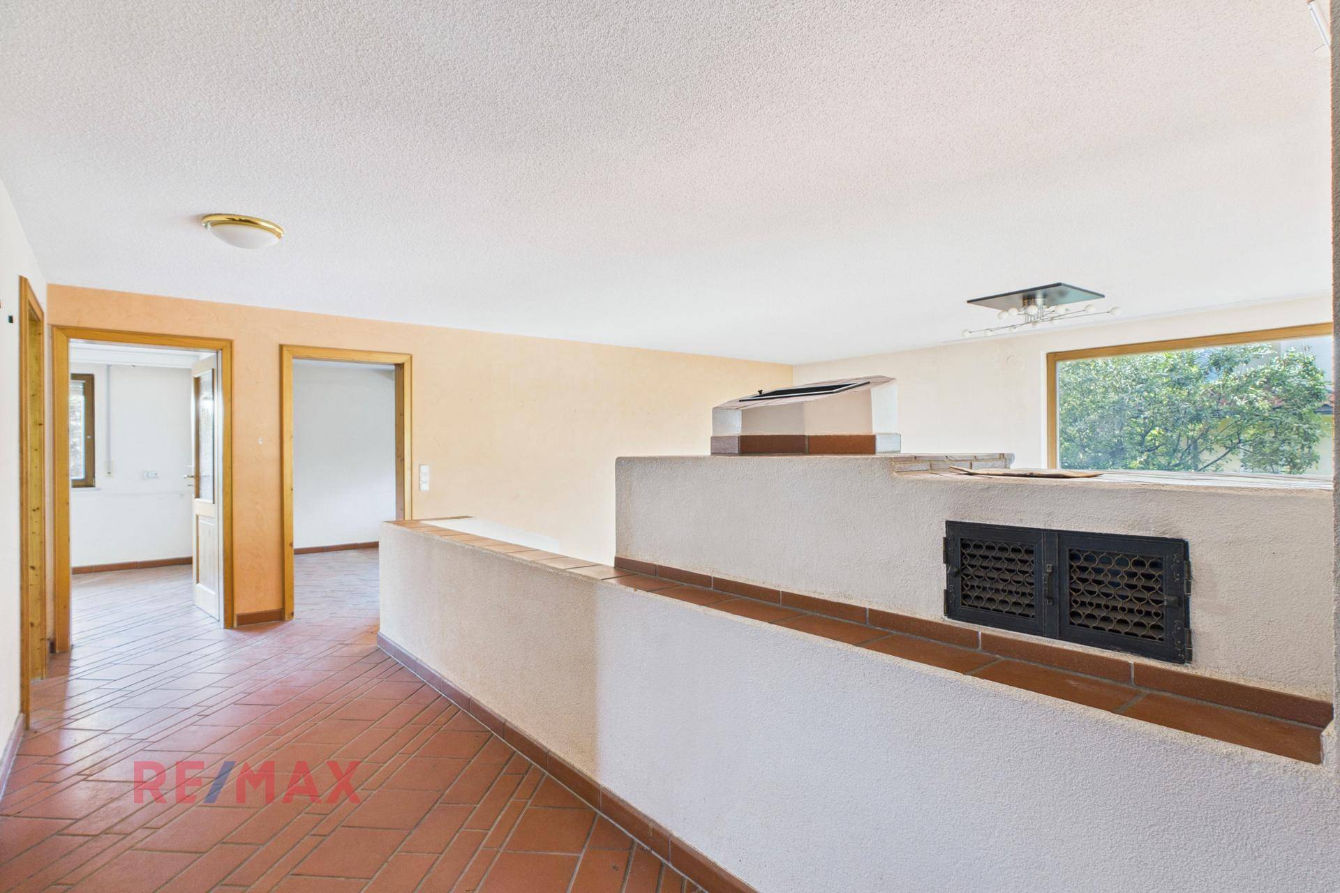 Übergangsbereich zum Wohnzimmer mit Terrakottafliesen und heller Wandfarbe, offen gestaltet.