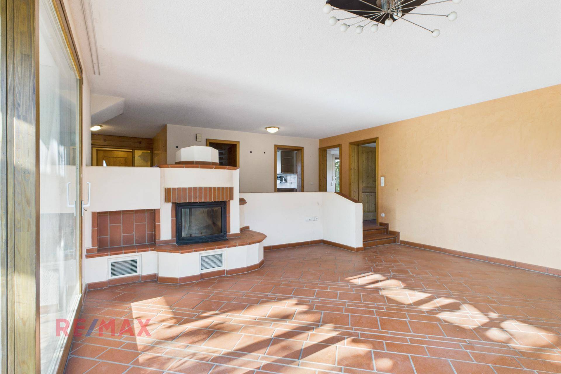 Helles Wohnzimmer mit traditionellem Kamin und Terrakottafliesen, ideal für gemütliche Abende.