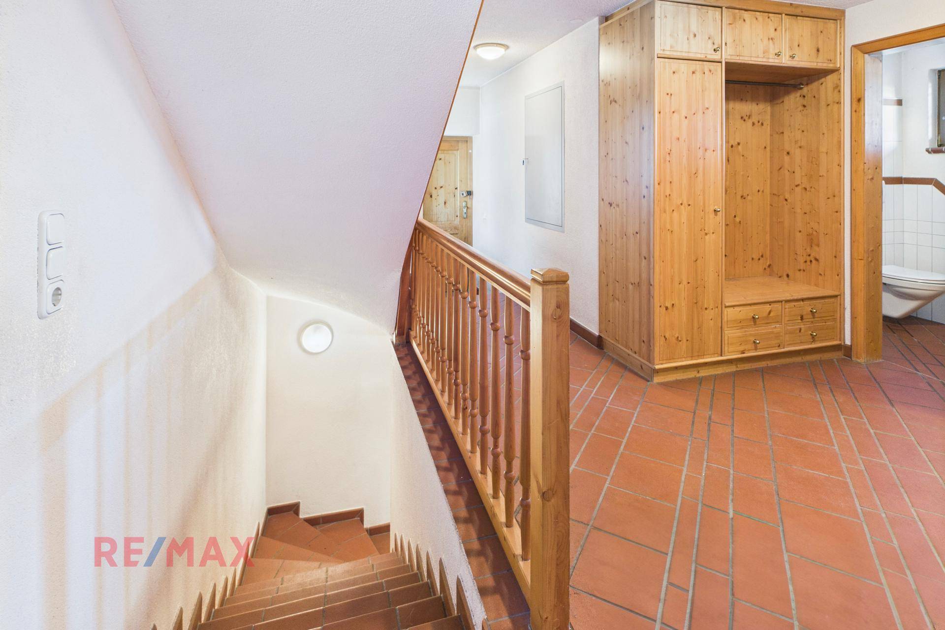 Treppenabgang zum Keller mit Holzgeländer und Einbauschrank, praktisch und funktional.