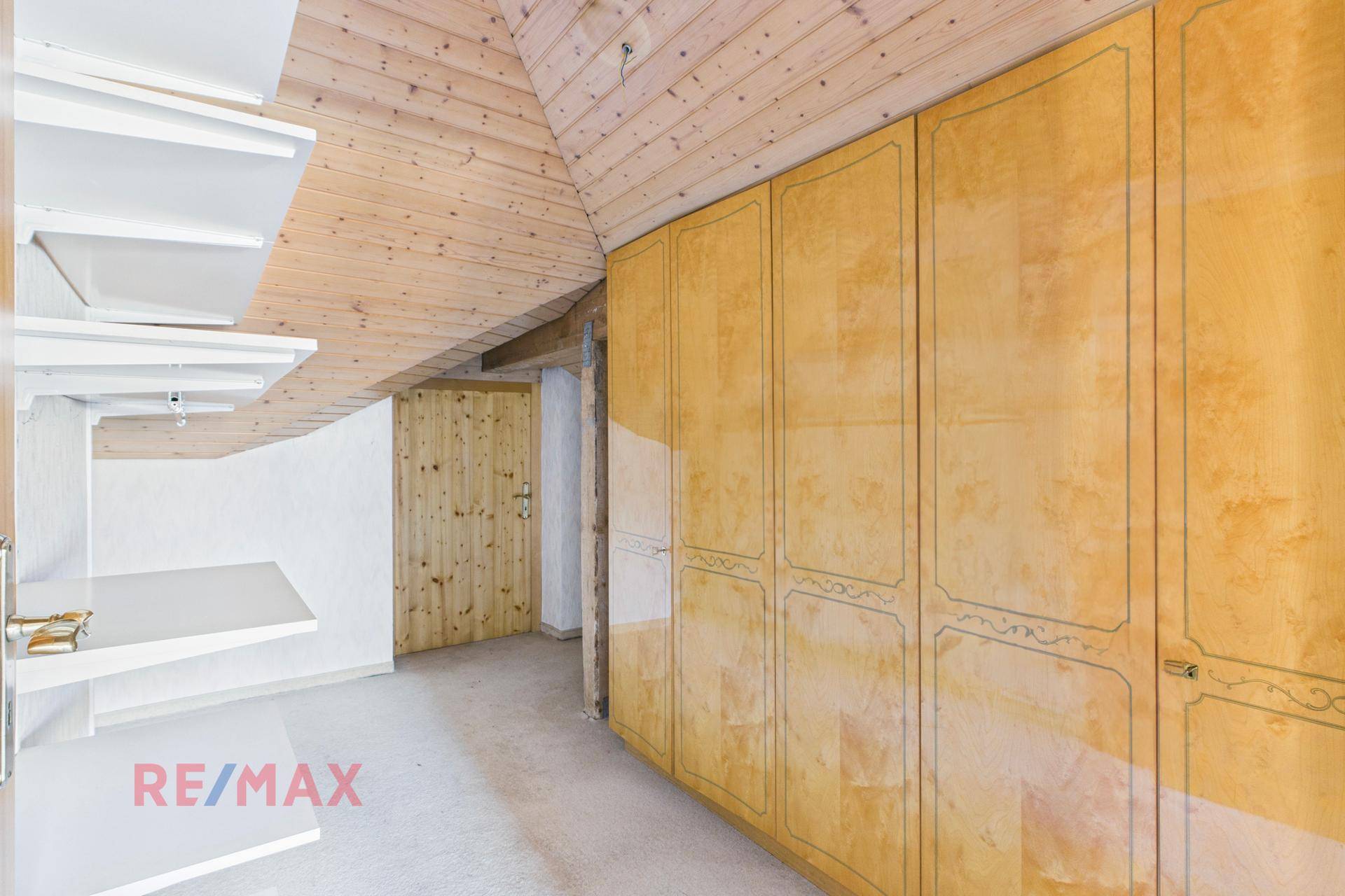 Dachzimmer mit Holzdecke und Einbauschränken, bietet praktischen Stauraum.