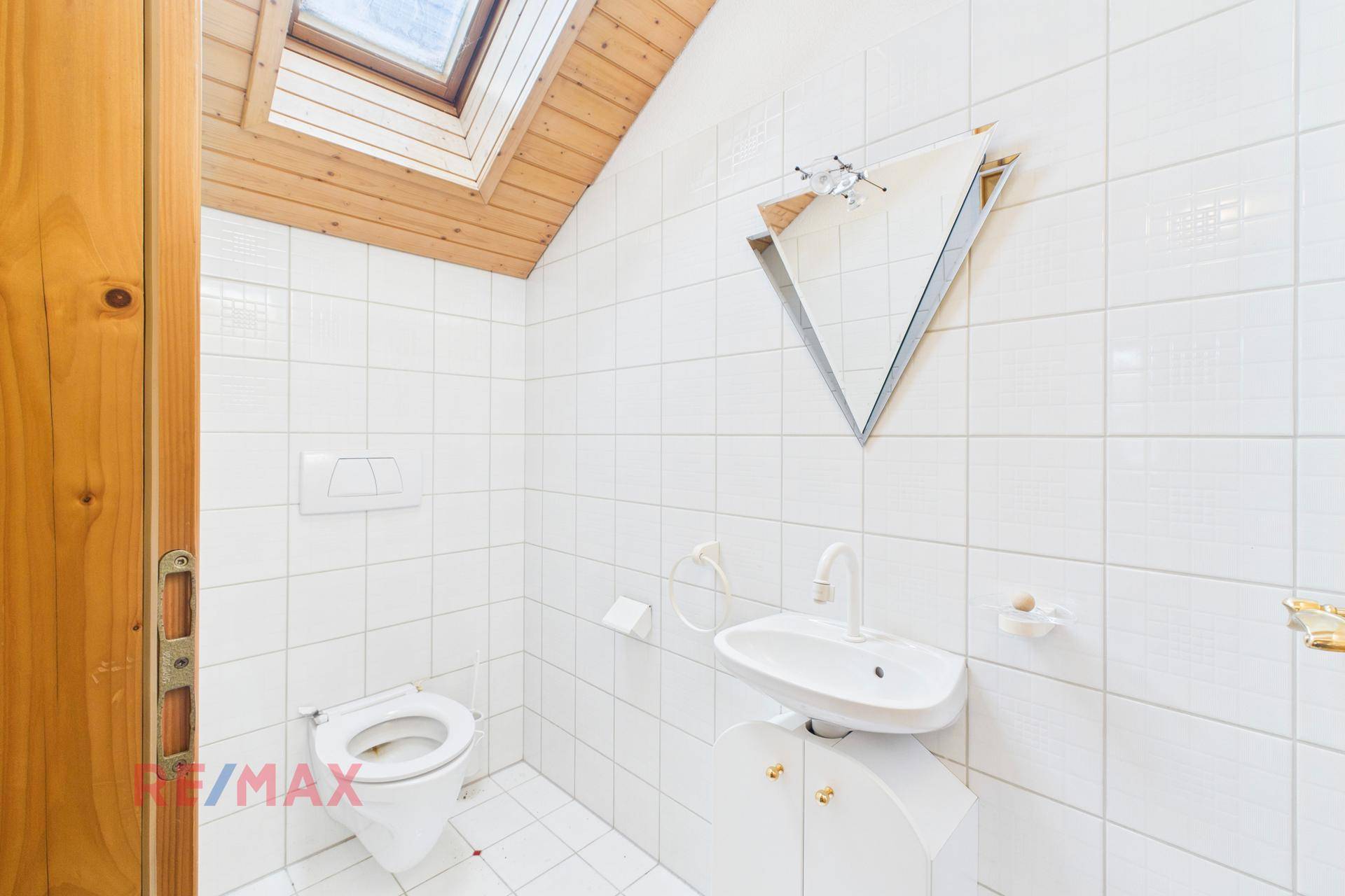 Separates WC mit Waschbecken, Fenster und Holzdecke, hell und funktional.