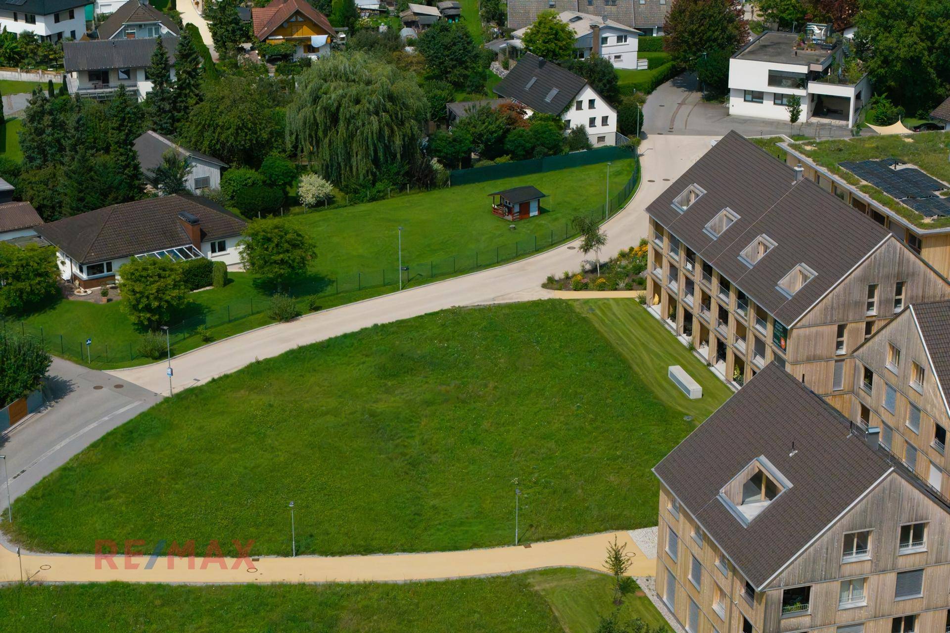 Luftaufnahme eines Baugrundstücks in einer ruhigen Wohngegend mit viel Grün und neuen Gebäuden.