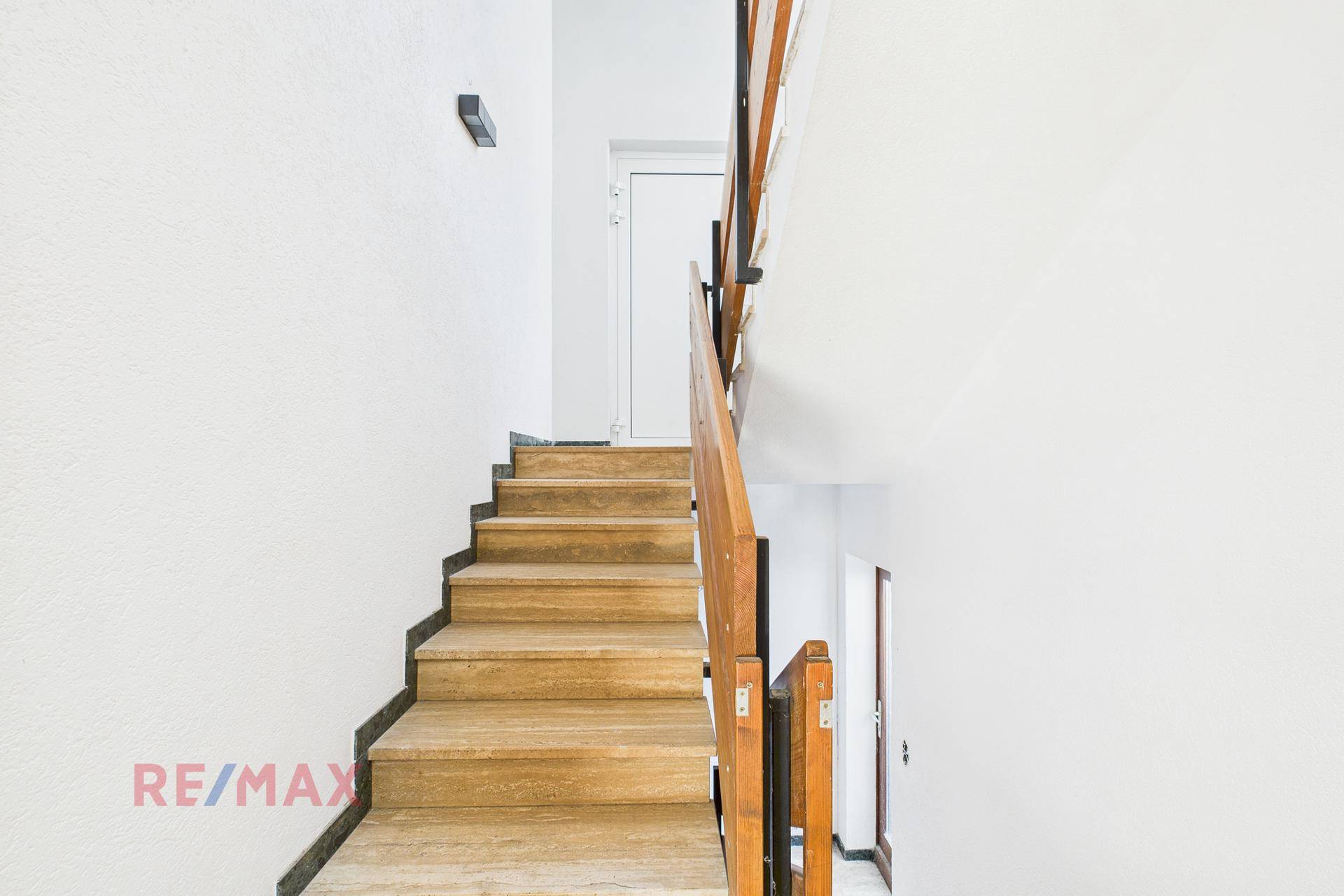 Treppenhaus mit Holzstufen und weiß gestrichenen Wänden, das die Etagen verbindet.