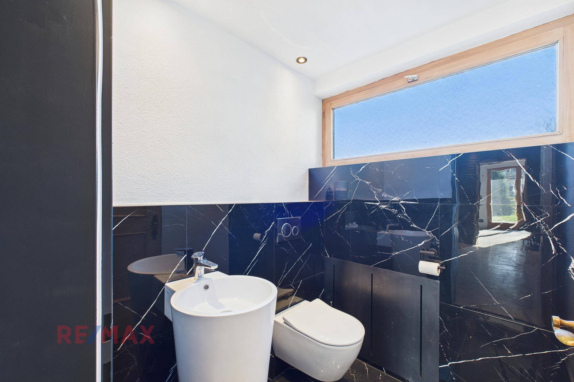 Modernes Gäste-WC mit schwarzen Marmorfliesen, wandhängendem WC und Fenster.
