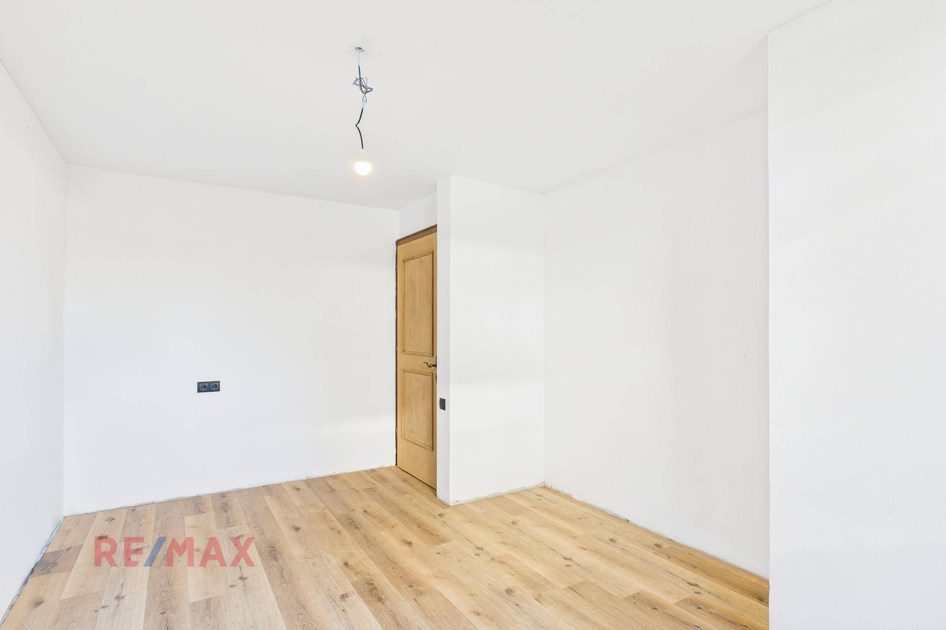 Schlafzimmer mit Parkettboden und Holztür, bereit für individuelle Gestaltung.