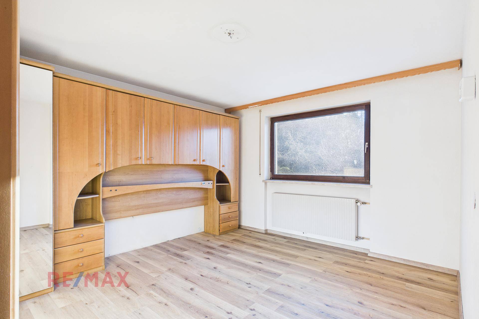 Schlafzimmer mit Einbauschränken aus Holz und Parkettboden, hell und funktional.