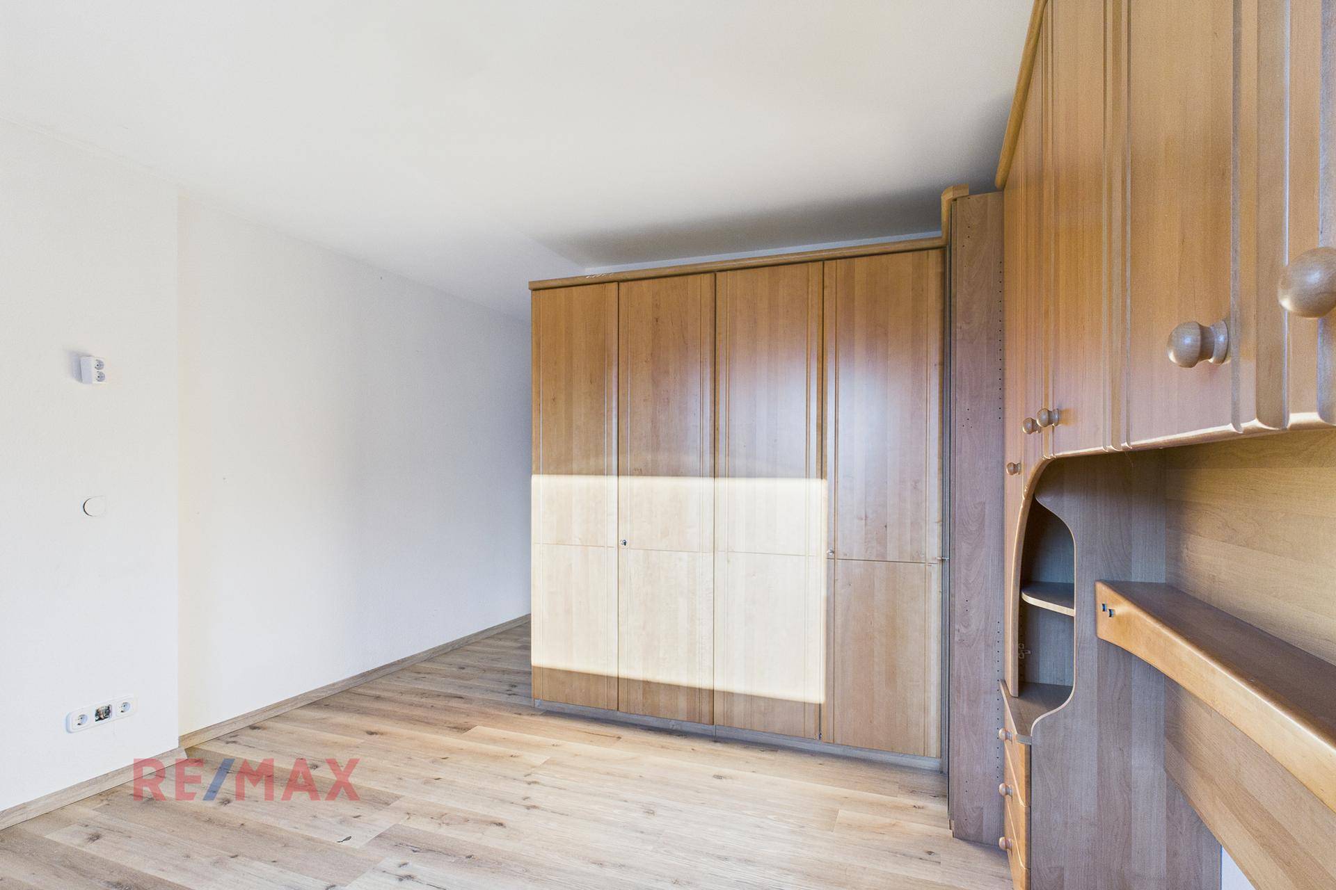 Schlafzimmer mit geräumigen Einbauschränken aus Holz und Parkettboden.