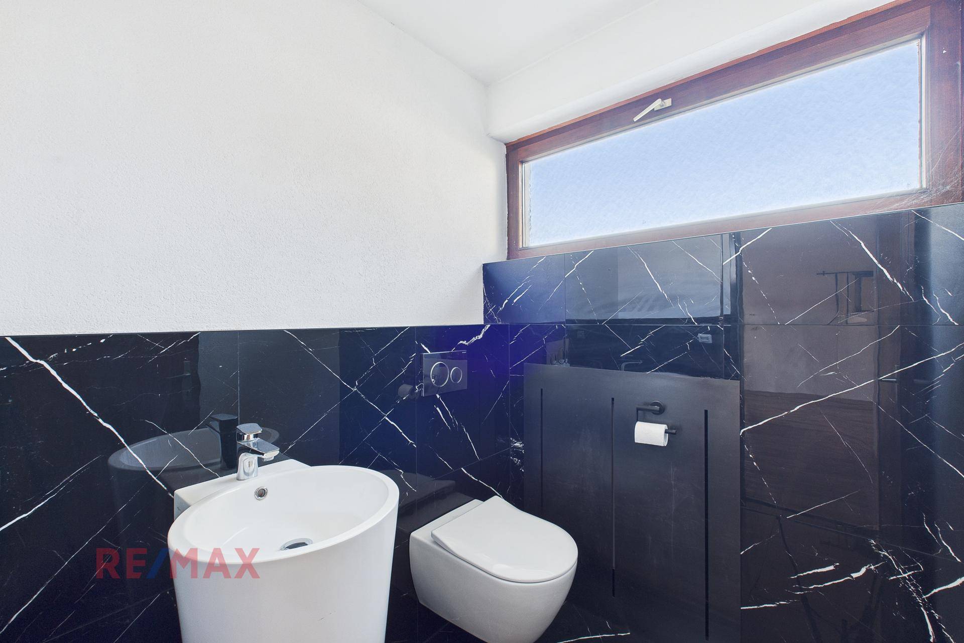 Modernes Gäste-WC mit schwarzen Marmorfliesen, wandhängendem WC und Fenster.