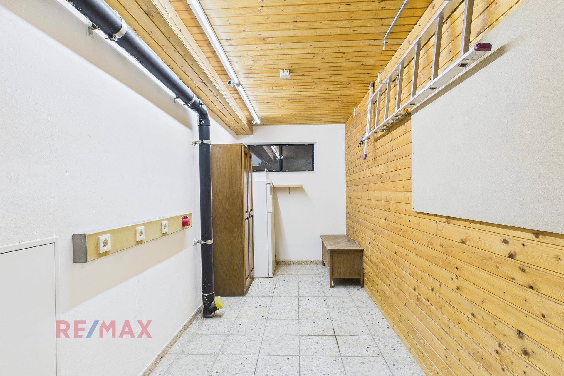 Abstellraum mit Holzverkleidung, Fliesenboden und Stauraum für diverse Gegenstände.