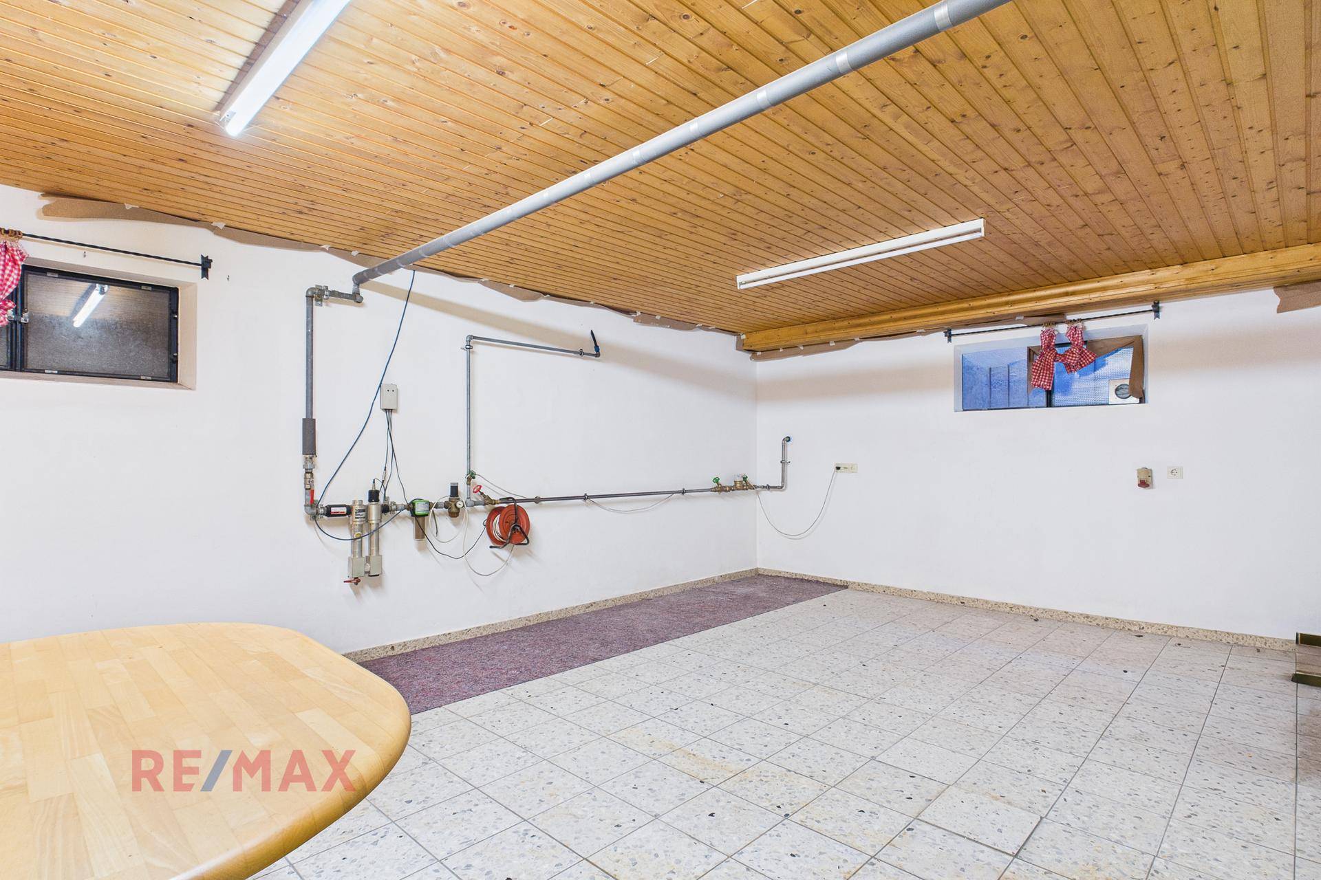 Geräumiger Hobbyraum oder Werkstatt mit Fliesenboden und Holzdecke.
