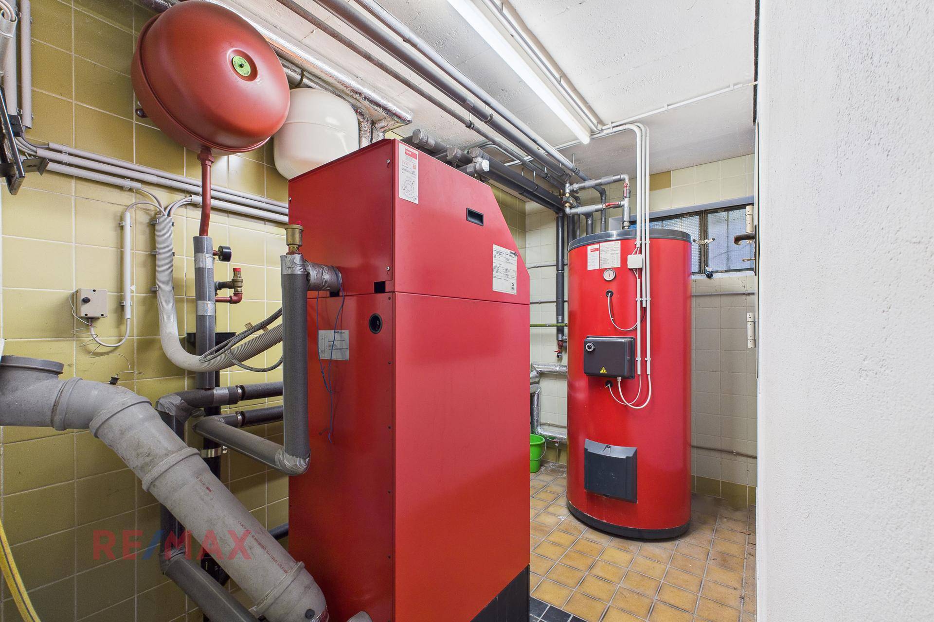 Heizraum mit rotem Heizkessel und Warmwasserspeicher, funktional und gut gewartet.