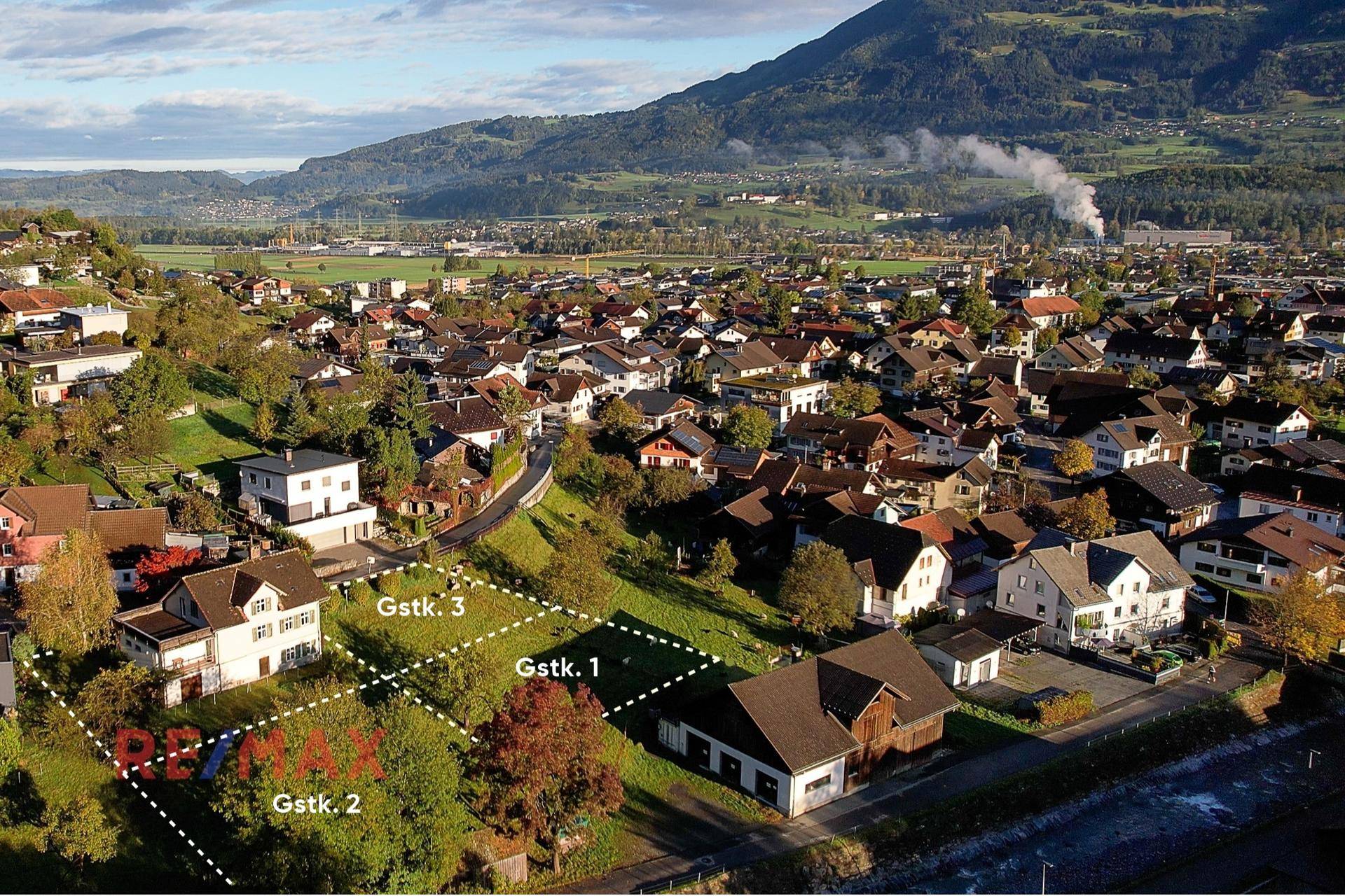 Luftaufnahme der Wohngegend mit markierten Grundstücksparzellen und Bergpanorama.