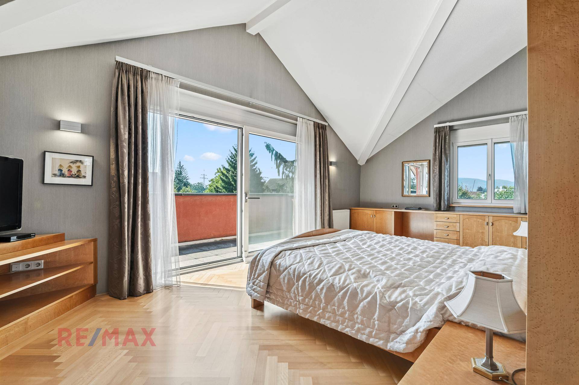 Geräumiges Schlafzimmer mit Parkettboden, Dachschrägen und Zugang zum Balkon.