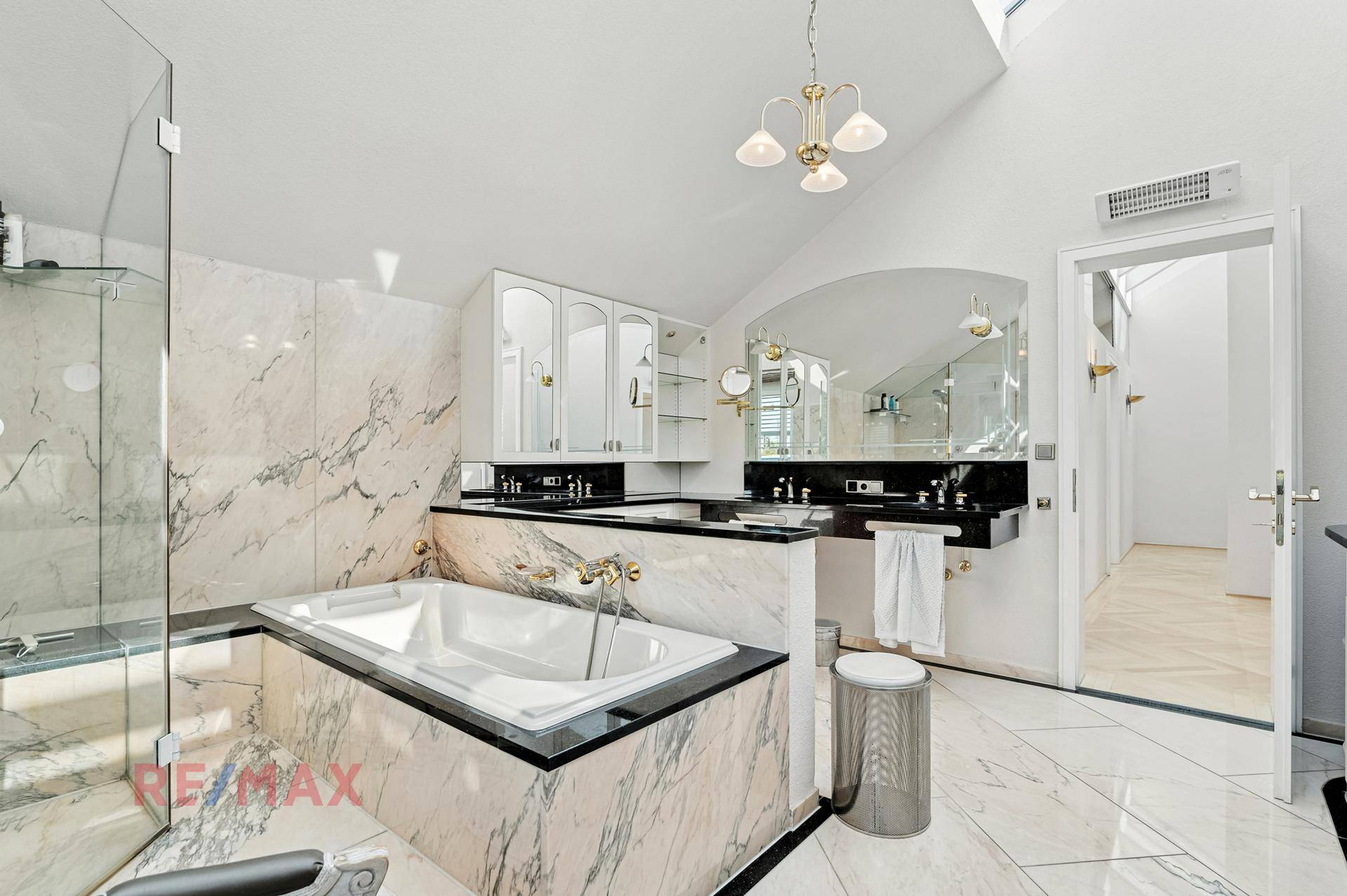 Luxuriöses Badezimmer mit Marmorfliesen, Badewanne und Doppelwaschbecken.