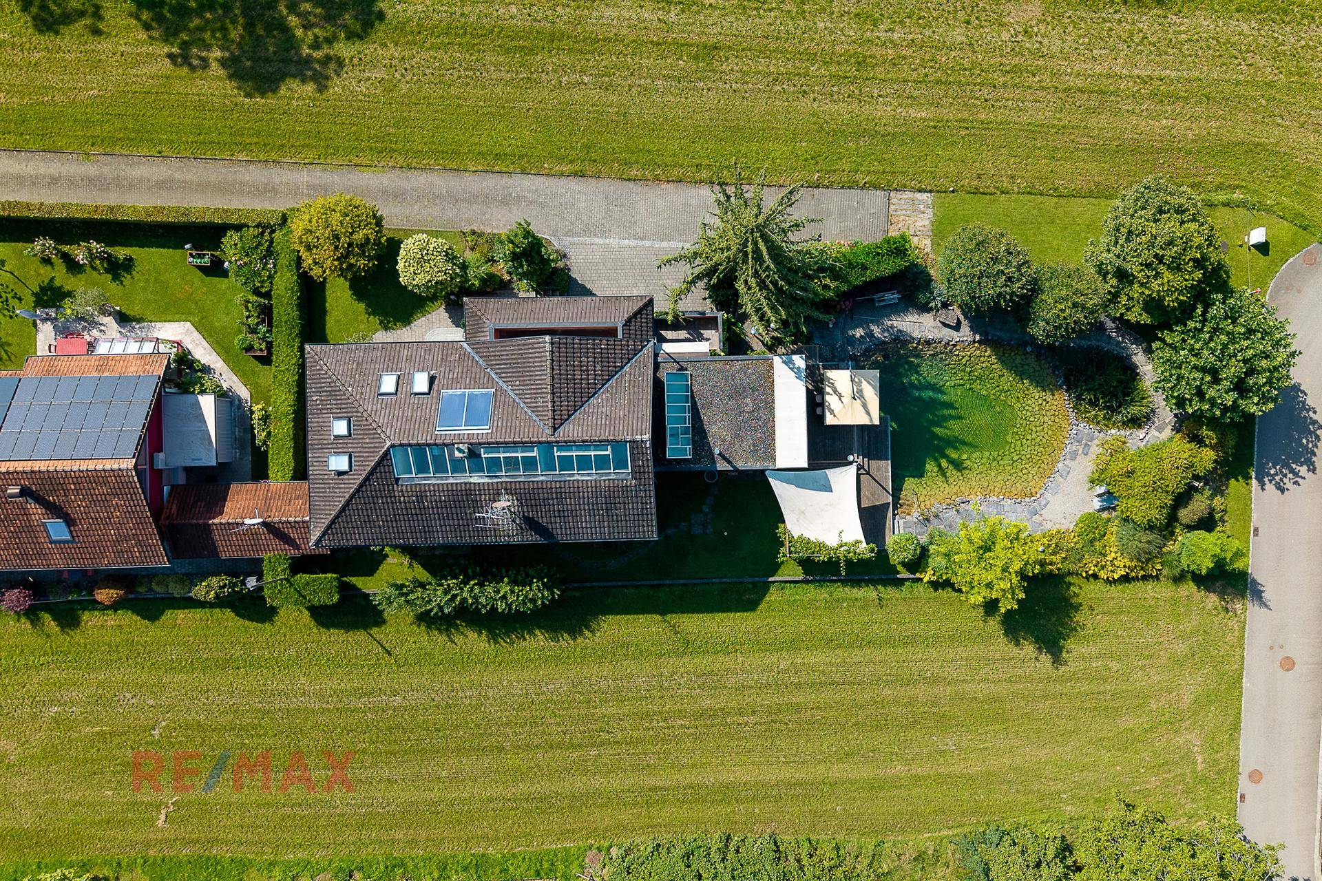 Luftaufnahme des Anwesens mit Haus, Garten, Teich und umliegenden Grünflächen.