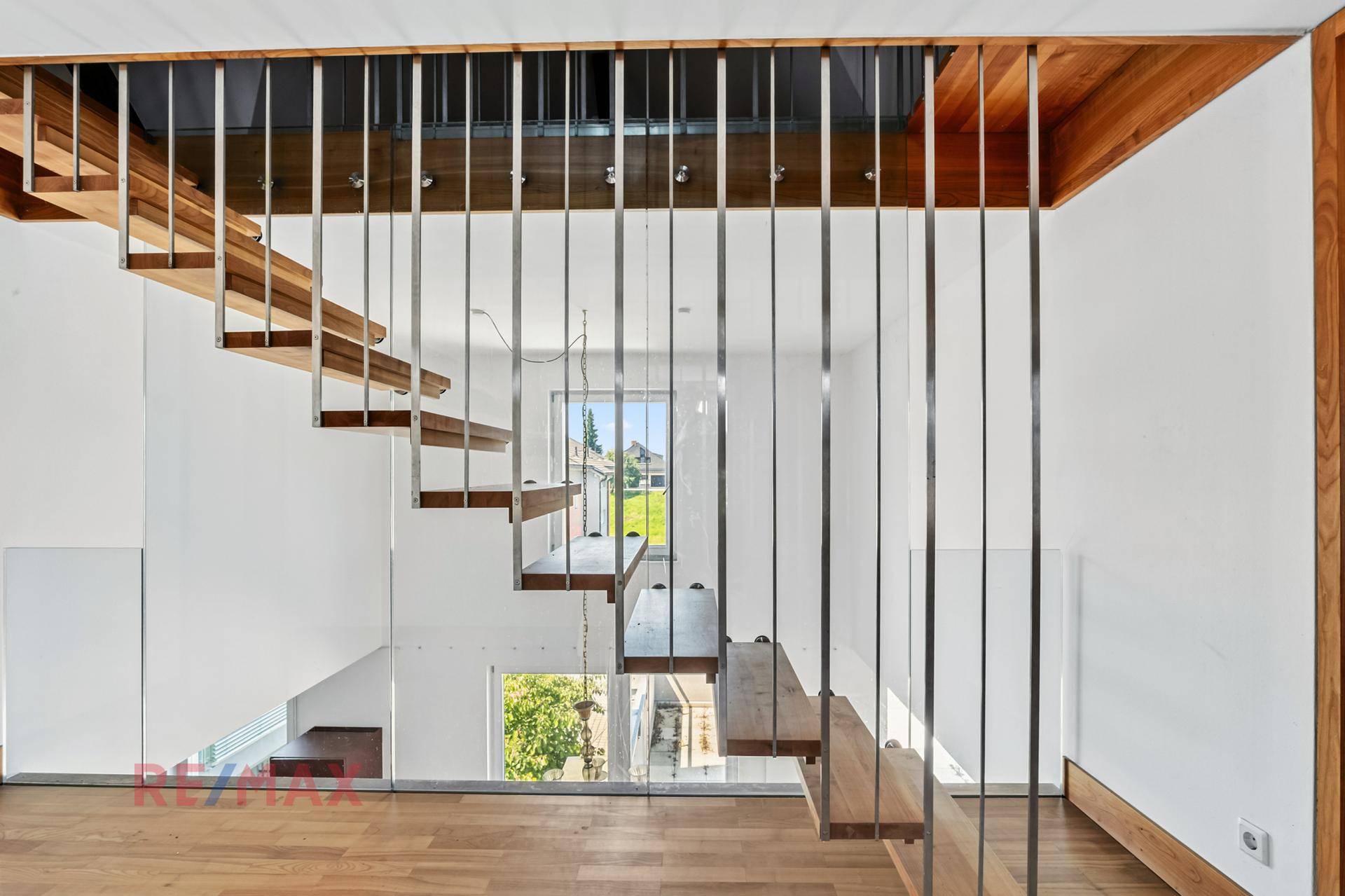 Elegante Holztreppe mit filigranem Geländer und offener Gestaltung, die Licht durchlässt.