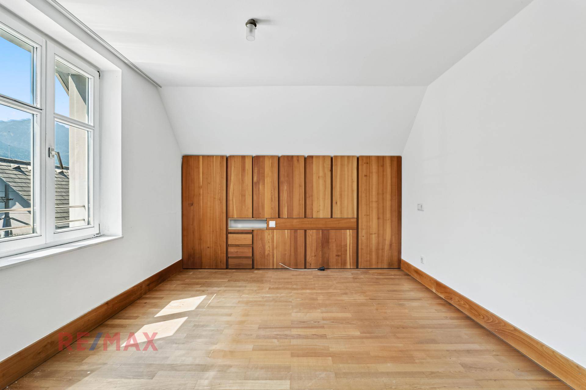 Geräumiges Zimmer mit Holzboden und integrierten Holzschränken, die viel Stauraum bieten.