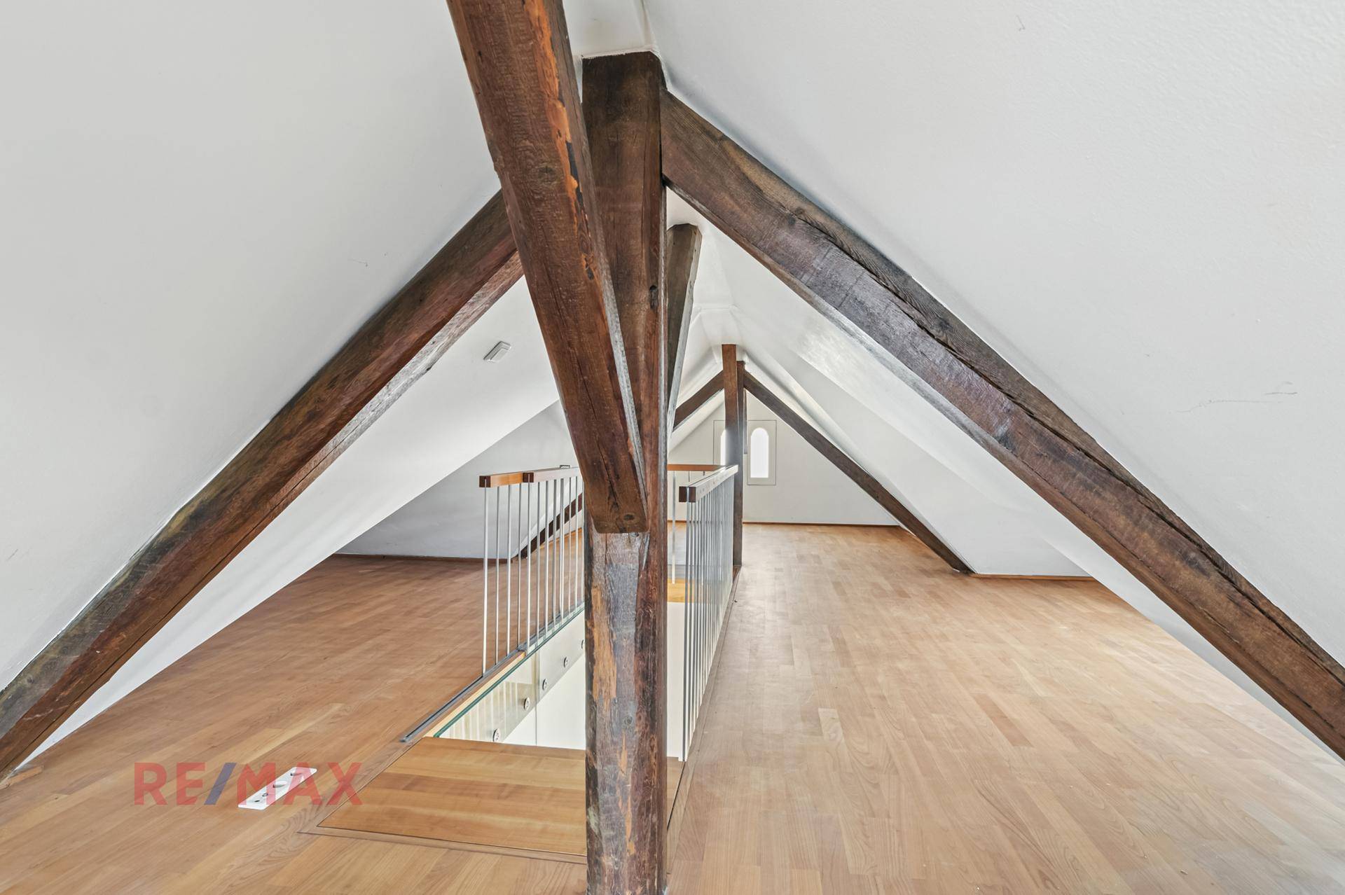 Offener Dachbodenbereich mit sichtbaren Holzbalken und Holzboden, der viel Potenzial bietet.