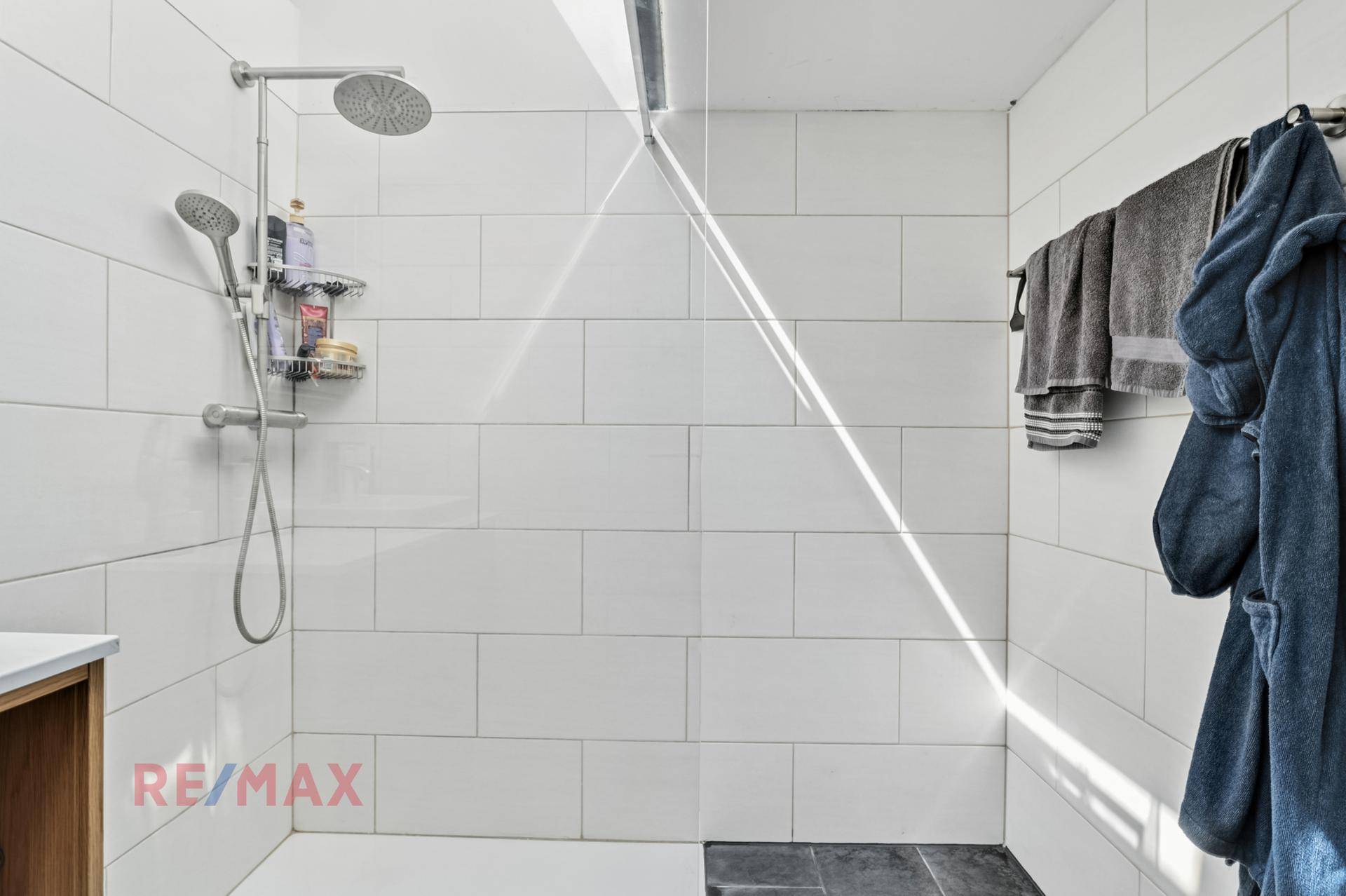 Geräumige begehbare Dusche mit Regenduschkopf und weißen Fliesen, die Komfort bietet.