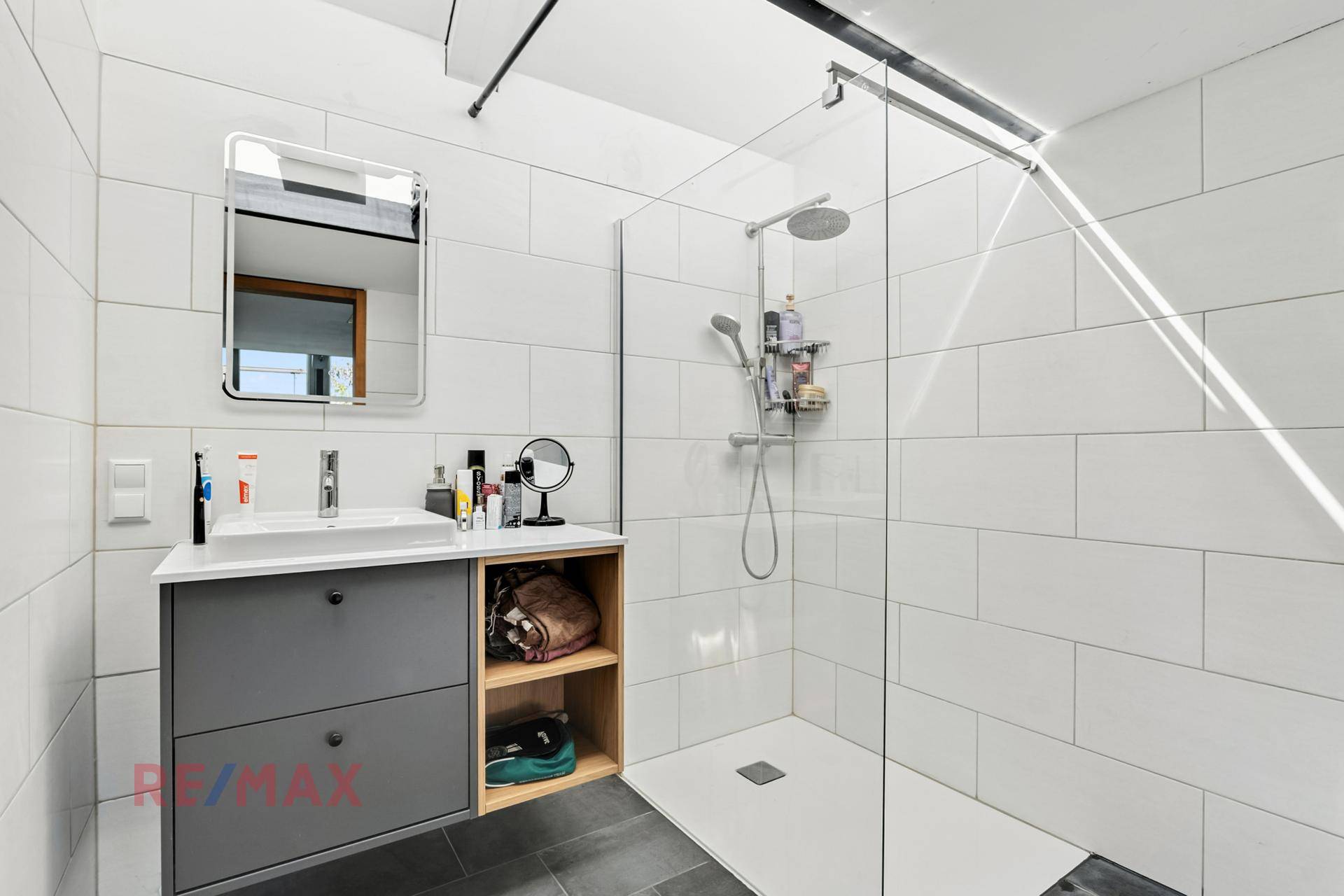 Modernes Badezimmer mit weiß gefliesten Wänden, begehbarer Dusche und elegantem Waschtisch.