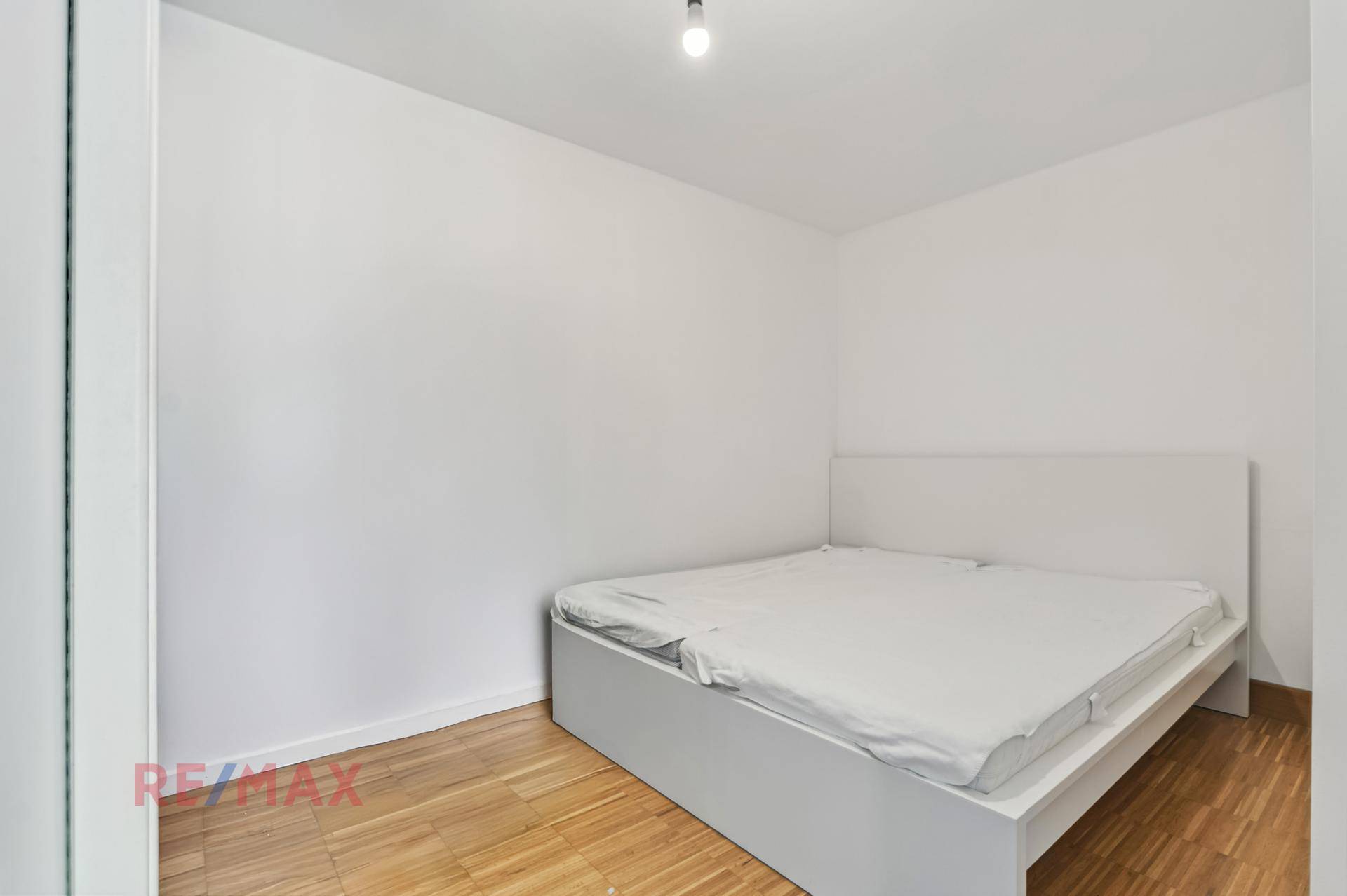 Einfaches Schlafzimmer mit Doppelbett und Holzboden, das eine ruhige Atmosphäre bietet.