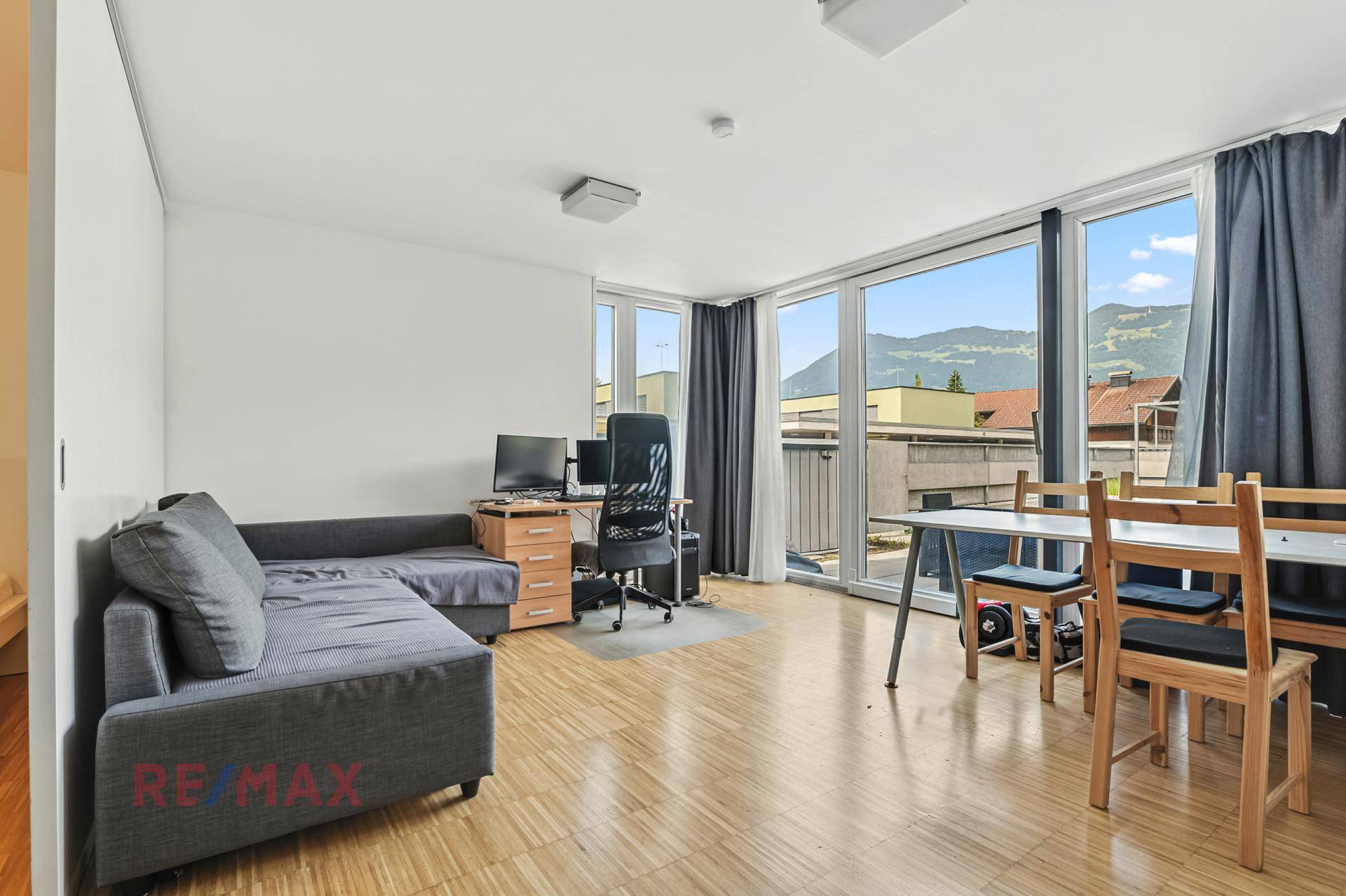 Heller Wohnraum mit großen Fenstern, Holzboden und Bergblick, der auch als Büro genutzt werden kann.