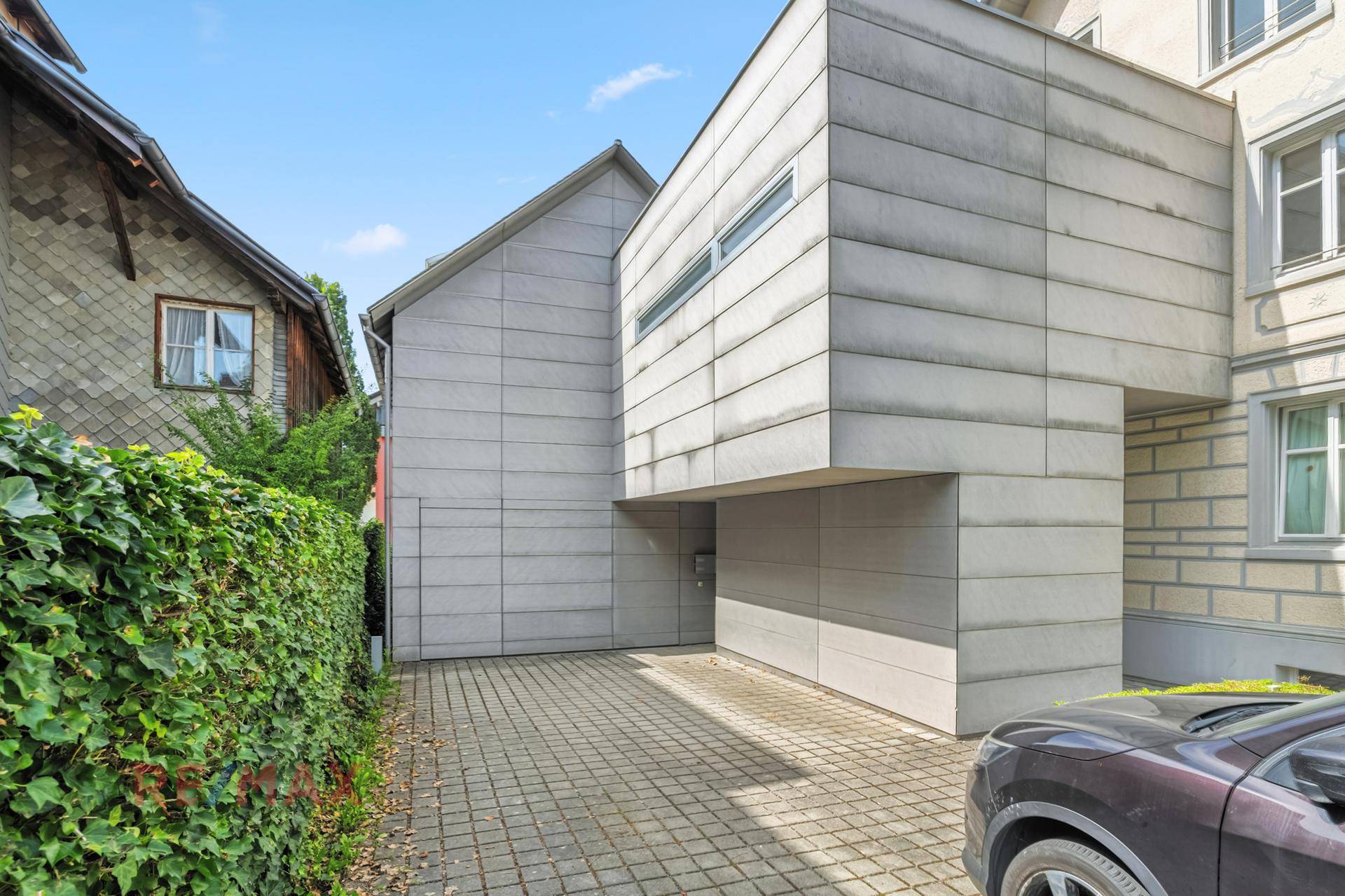 Moderne Gebäudefassade mit Zufahrt und integrierter Garage, die Funktionalität bietet.