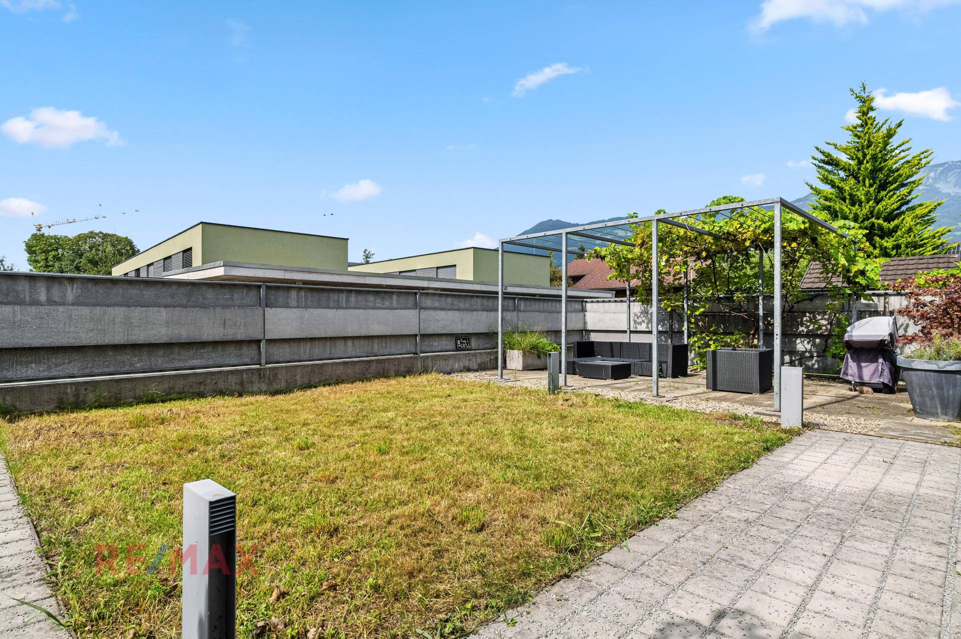 Gepflegter Gartenbereich mit Rasenfläche, Pergola und Grillplatz, ideal für Outdoor-Aktivitäten.