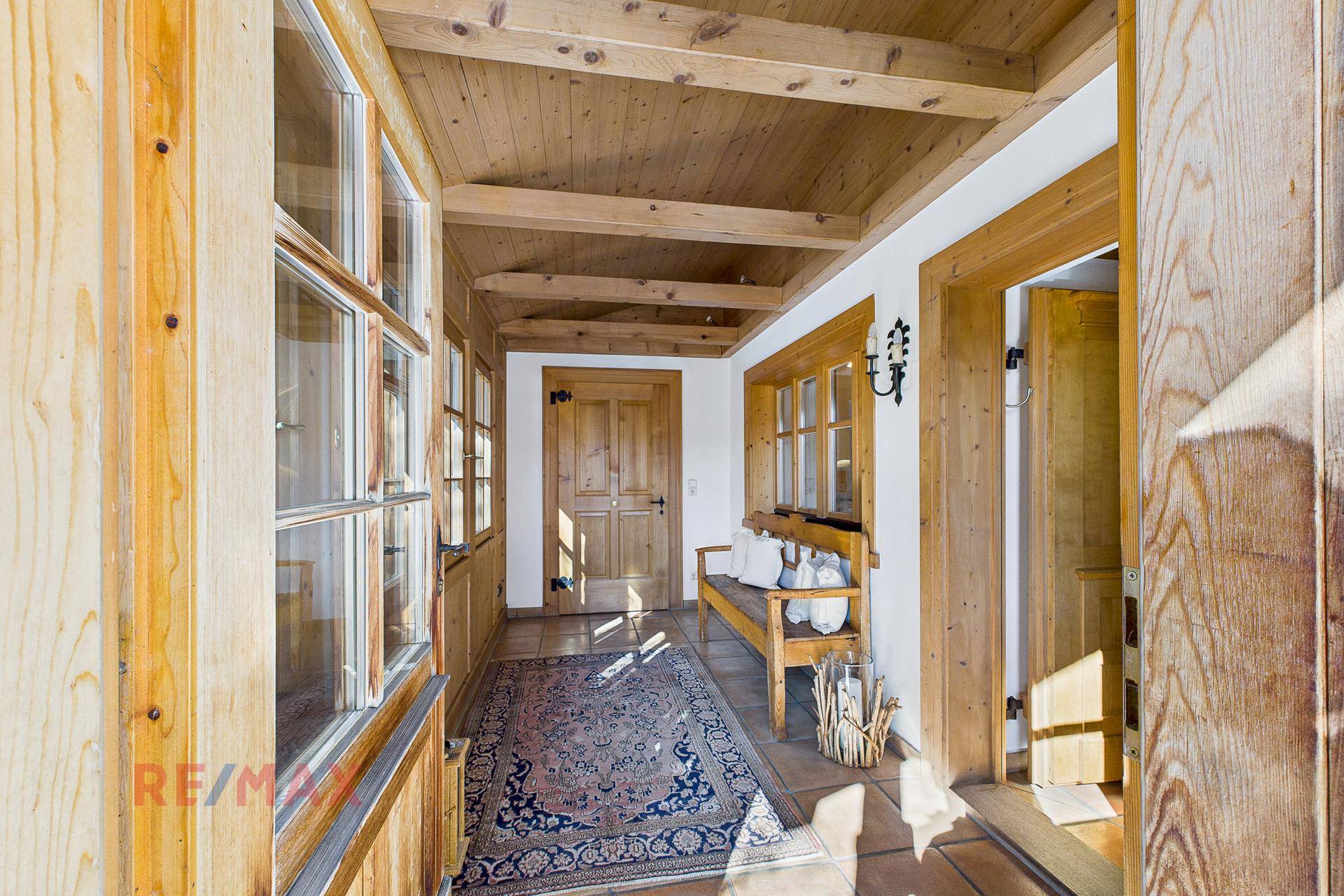Gemütlicher Flur mit Holzbalkendecke, Terrakottafliesen und traditionellem Teppich.