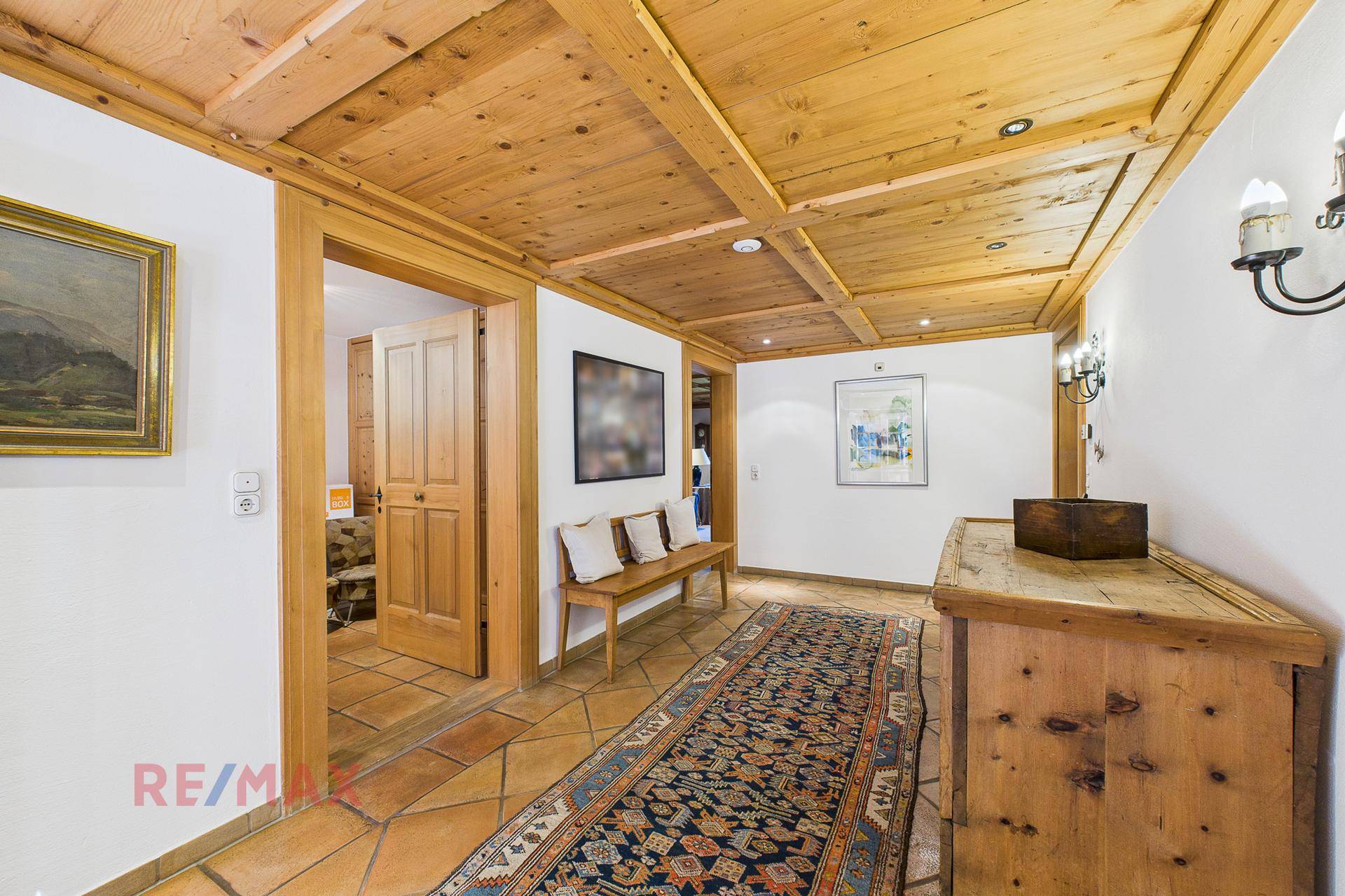Geräumiger Flur mit Holzbalkendecke, Terrakottafliesen und traditionellen Möbeln.