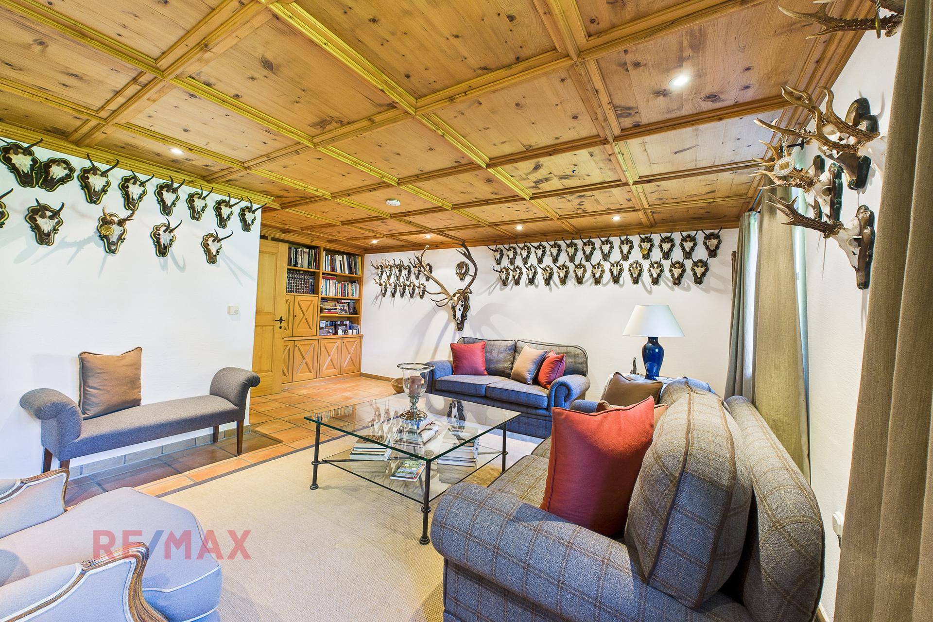 Großzügiges Wohnzimmer mit Holzkassettendecke, bequemen Sofas und traditioneller Dekoration.
