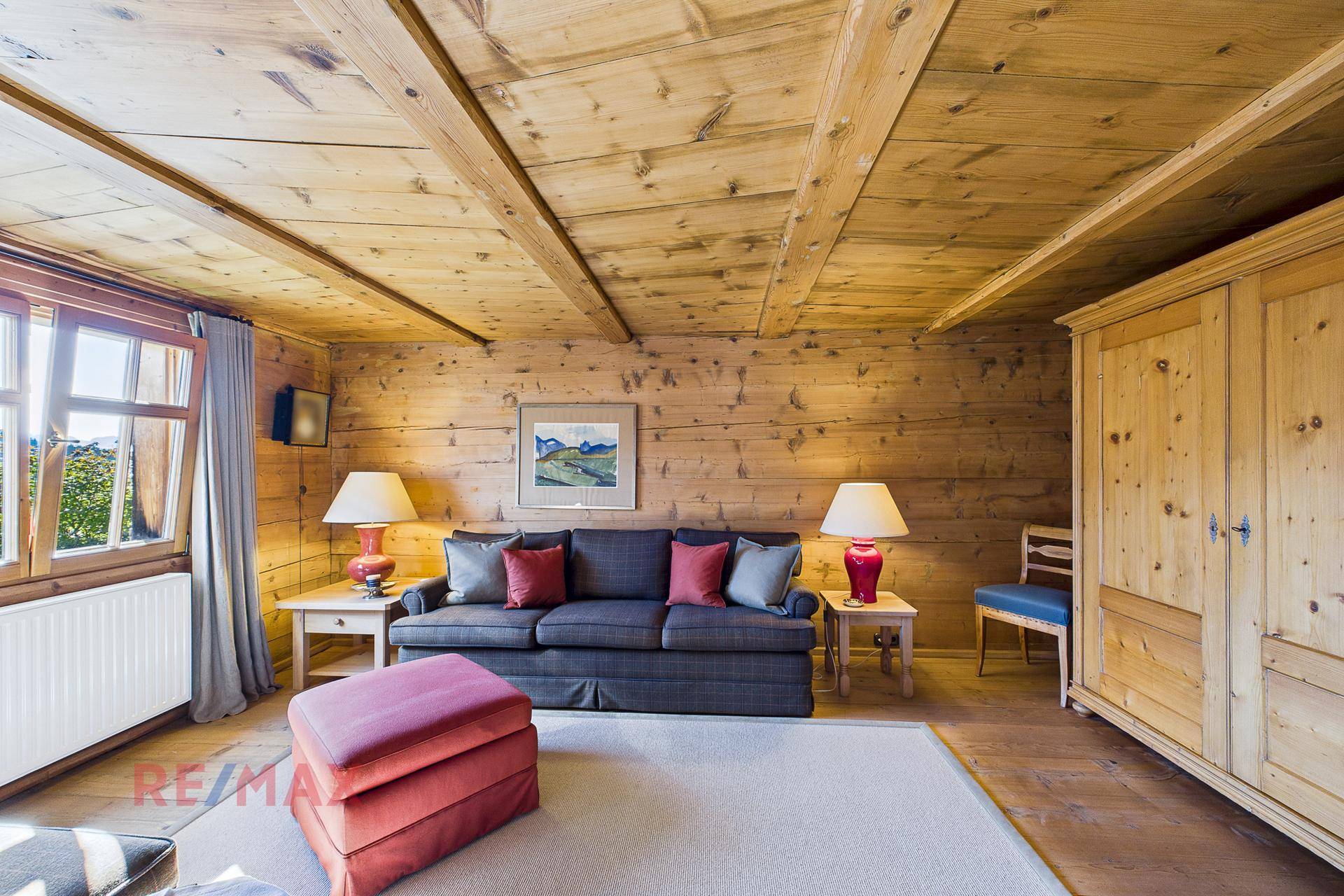 Wohnzimmer im Landhausstil mit Holzwänden, Teppichboden und traditionellem Kleiderschrank.