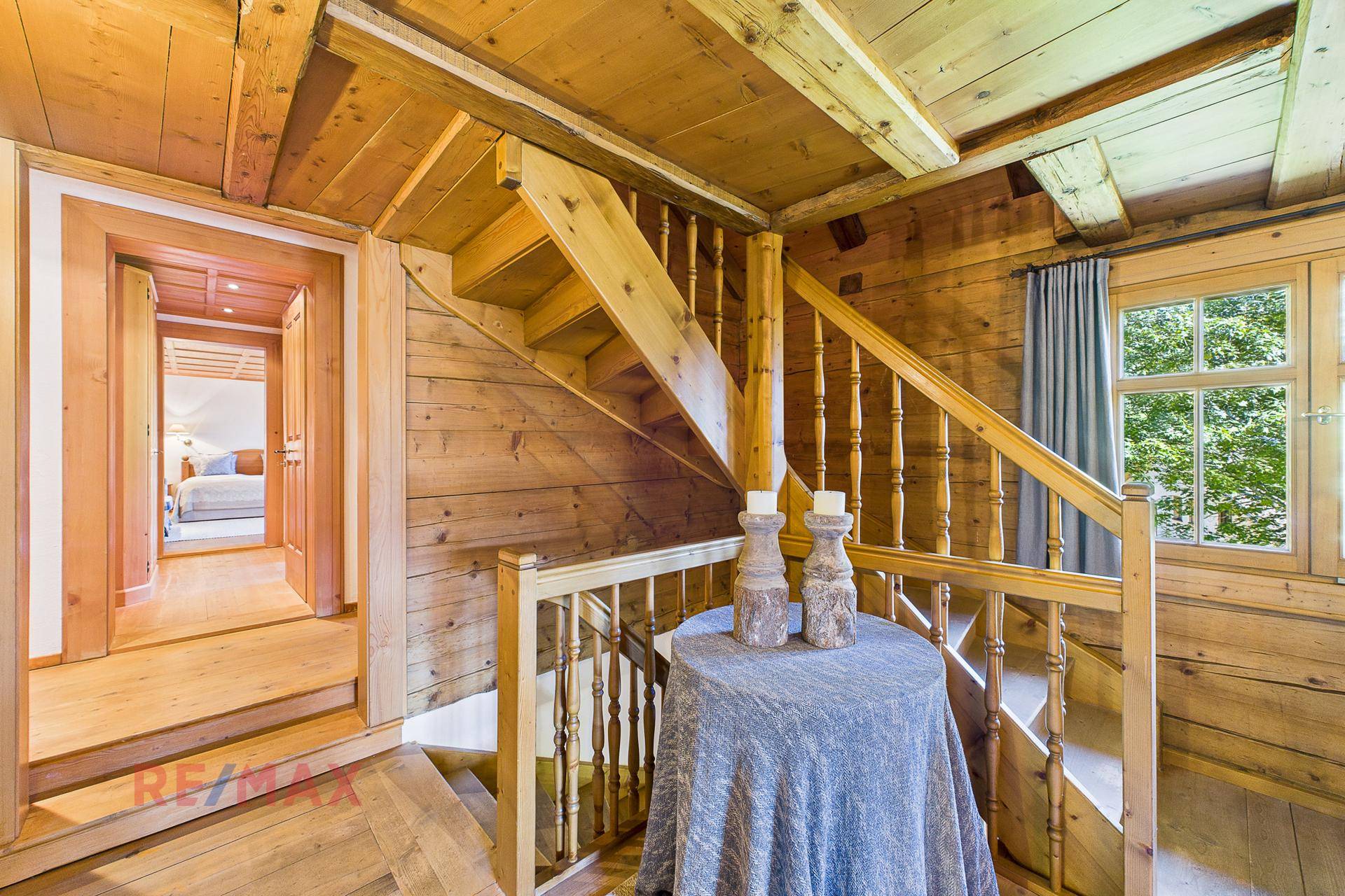 Holztreppe führt in die obere Etage, umgeben von rustikalen Holzwänden und -decken.