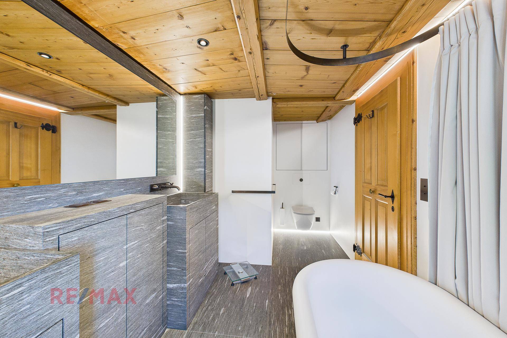 Modernes Badezimmer mit freistehender Badewanne, Steinwaschtisch und Holzdecke.
