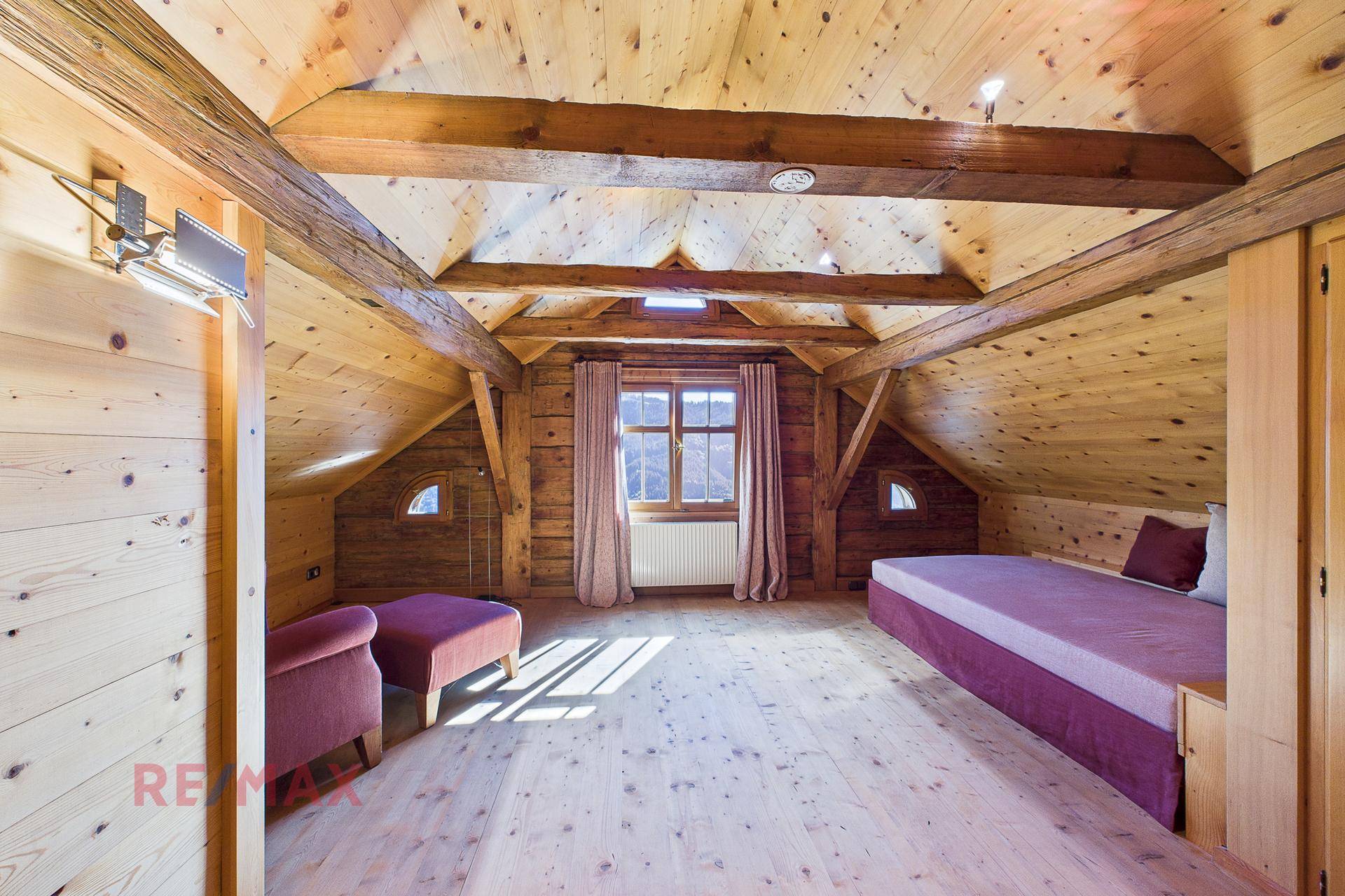 Geräumiger Dachboden mit Holzbalken, Dachschrägen und Fenster mit Bergblick.
