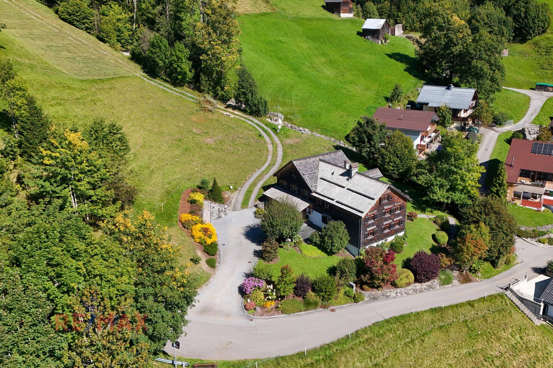 Luftaufnahme des Anwesens mit gepflegtem Garten und umliegender Natur.