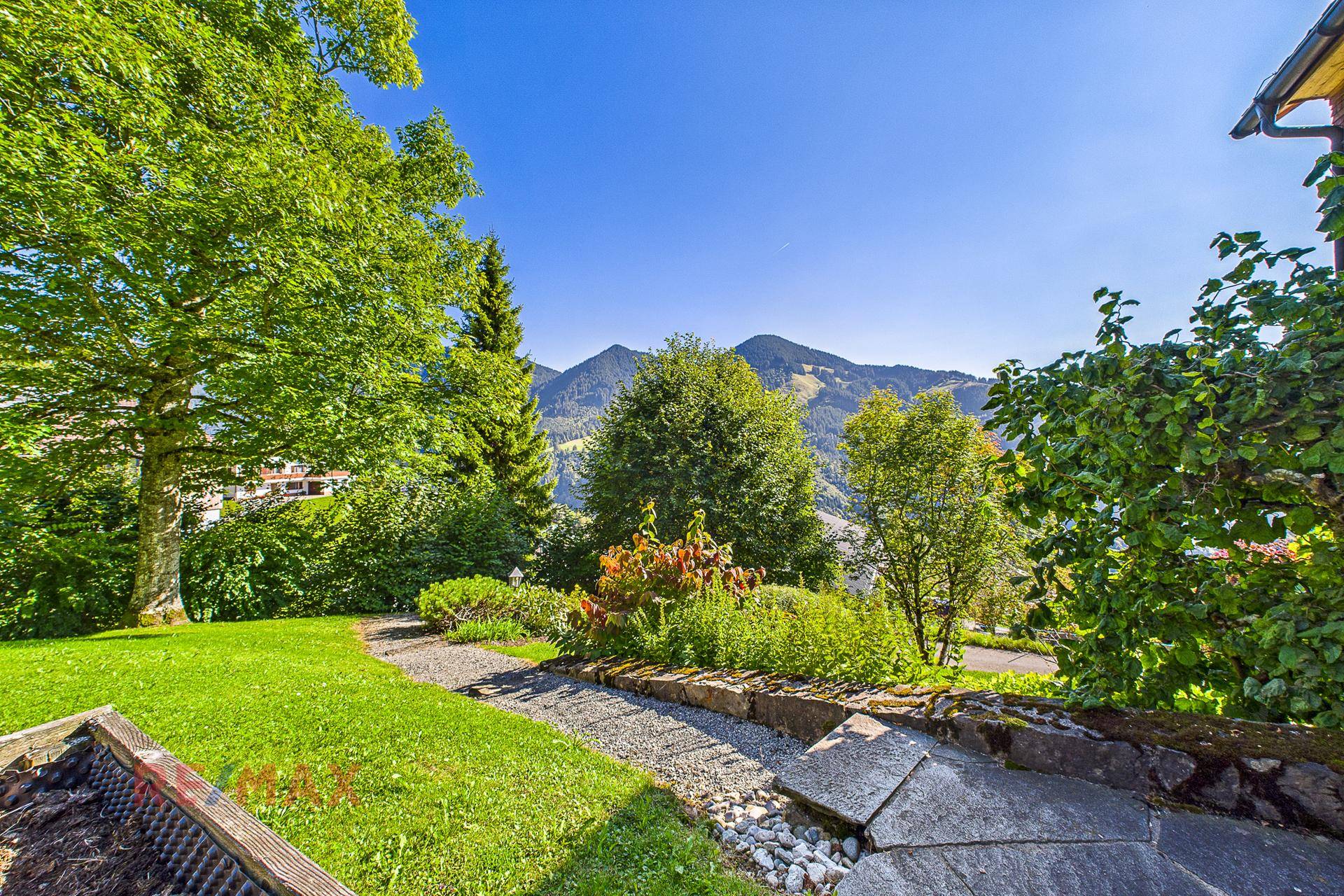 Gepflegter Gartenbereich mit Kieswegen und weitem Blick auf die umliegenden Berge.