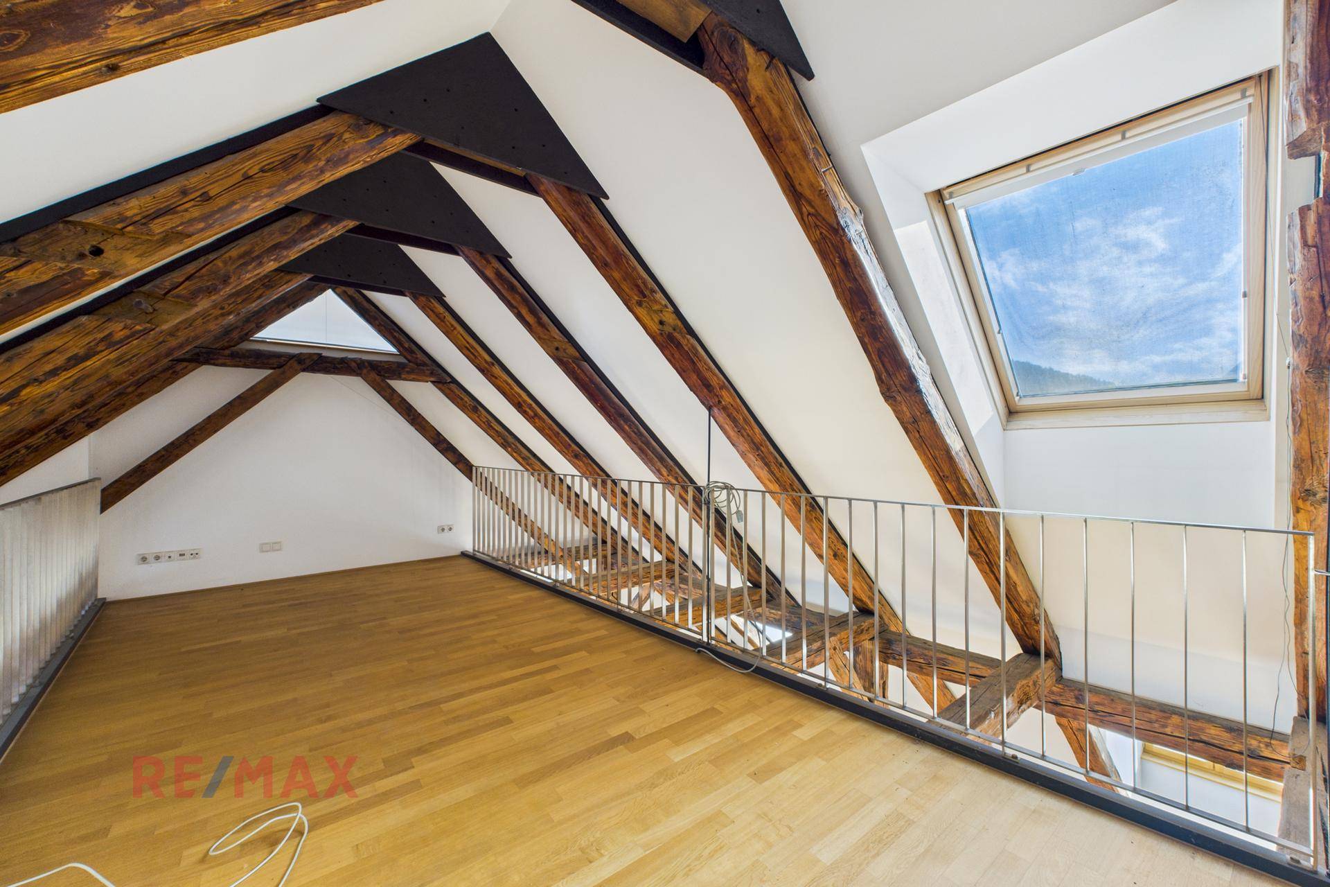 Offene Galerie im Dachgeschoss mit Holzbalken, hellem Parkett und Blick auf den unteren Wohnbereich.