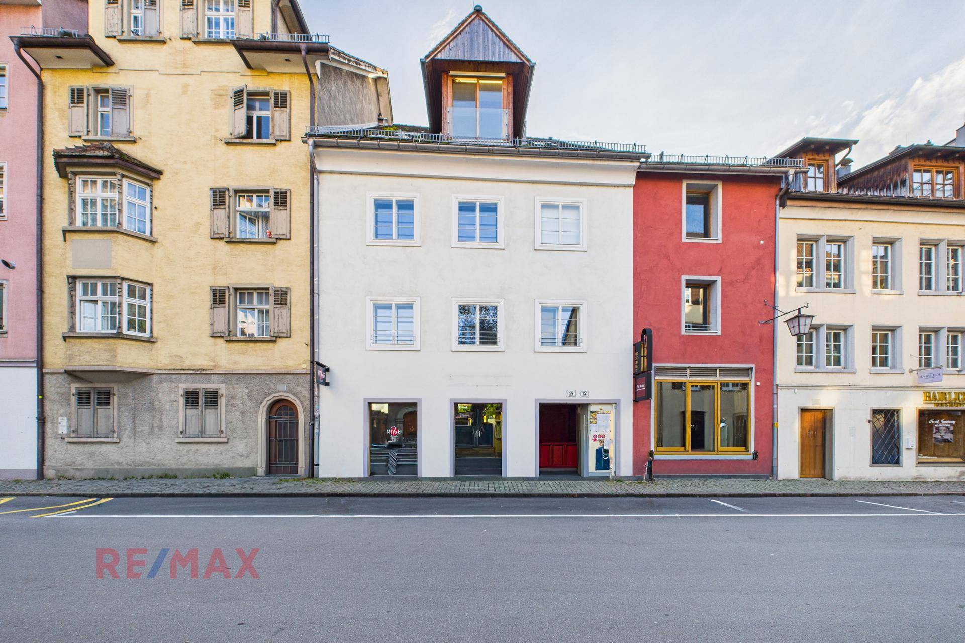 Historisches Gebäude mit weißer Fassade und mehreren Fenstern, gelegen an einer städtischen Straße.
