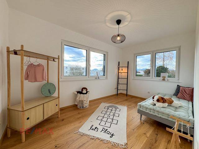 Kinderzimmer mit Holzboden, großen Fenstern und kindgerechter Dekoration, hell und freundlich.