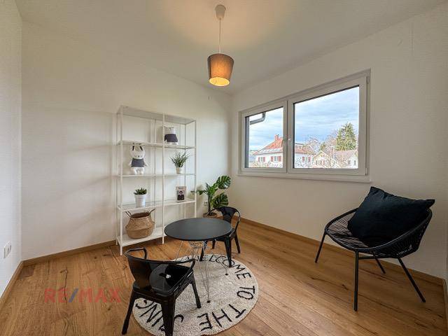 Helles Zimmer mit Holzboden, Fenster und einfacher Einrichtung, ideal als Büro oder Gästezimmer.