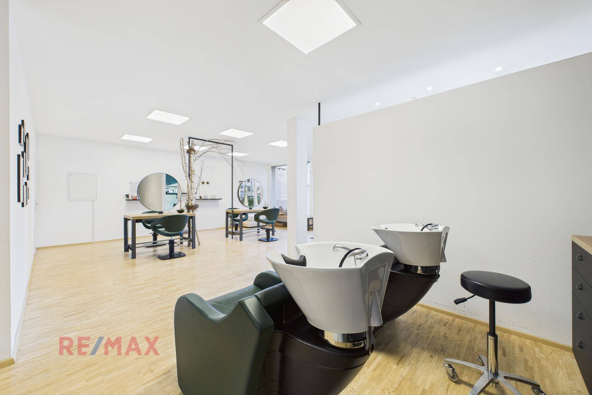 Heller Haarwaschbereich mit zwei Stühlen und Blick auf den Hauptsalonbereich.