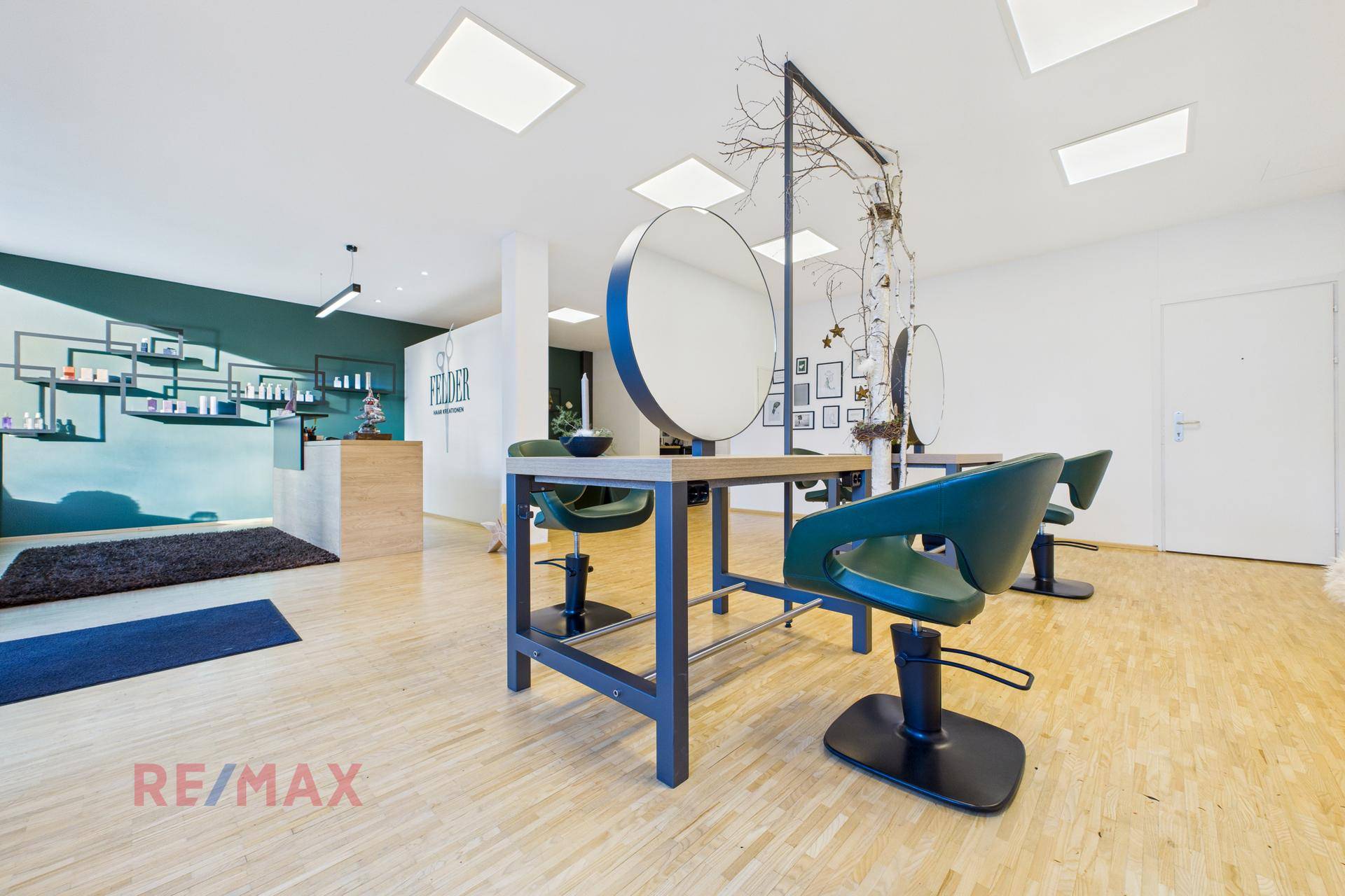 Geräumiger Friseursalon mit mehreren Bedienplätzen, großen Spiegeln und Holzfußboden.