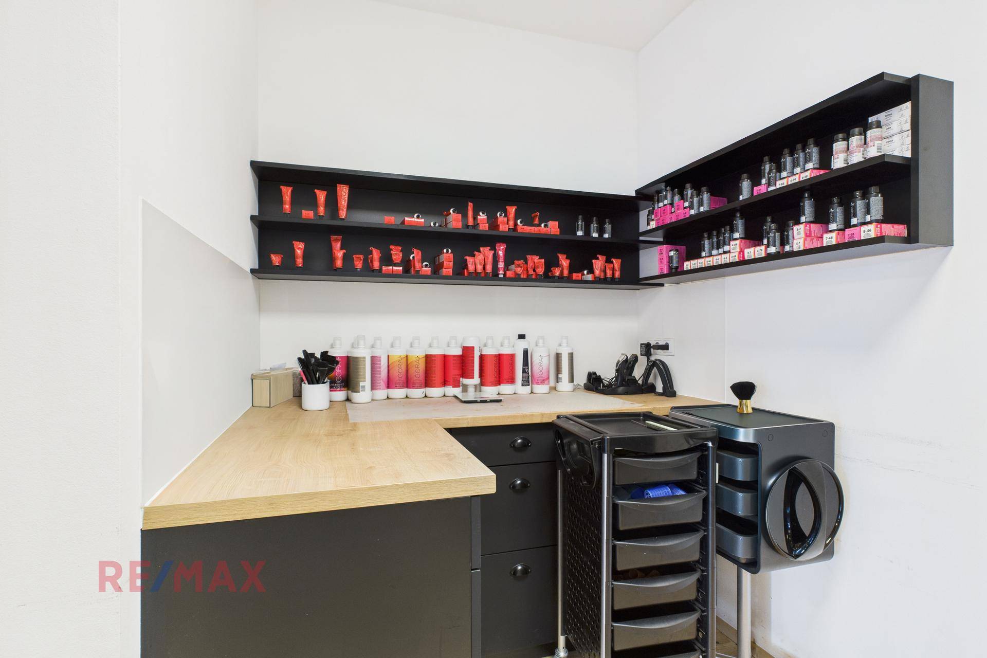 Praktischer Arbeitsbereich mit Holztheke, schwarzen Regalen und Produkten für den Salonbedarf.