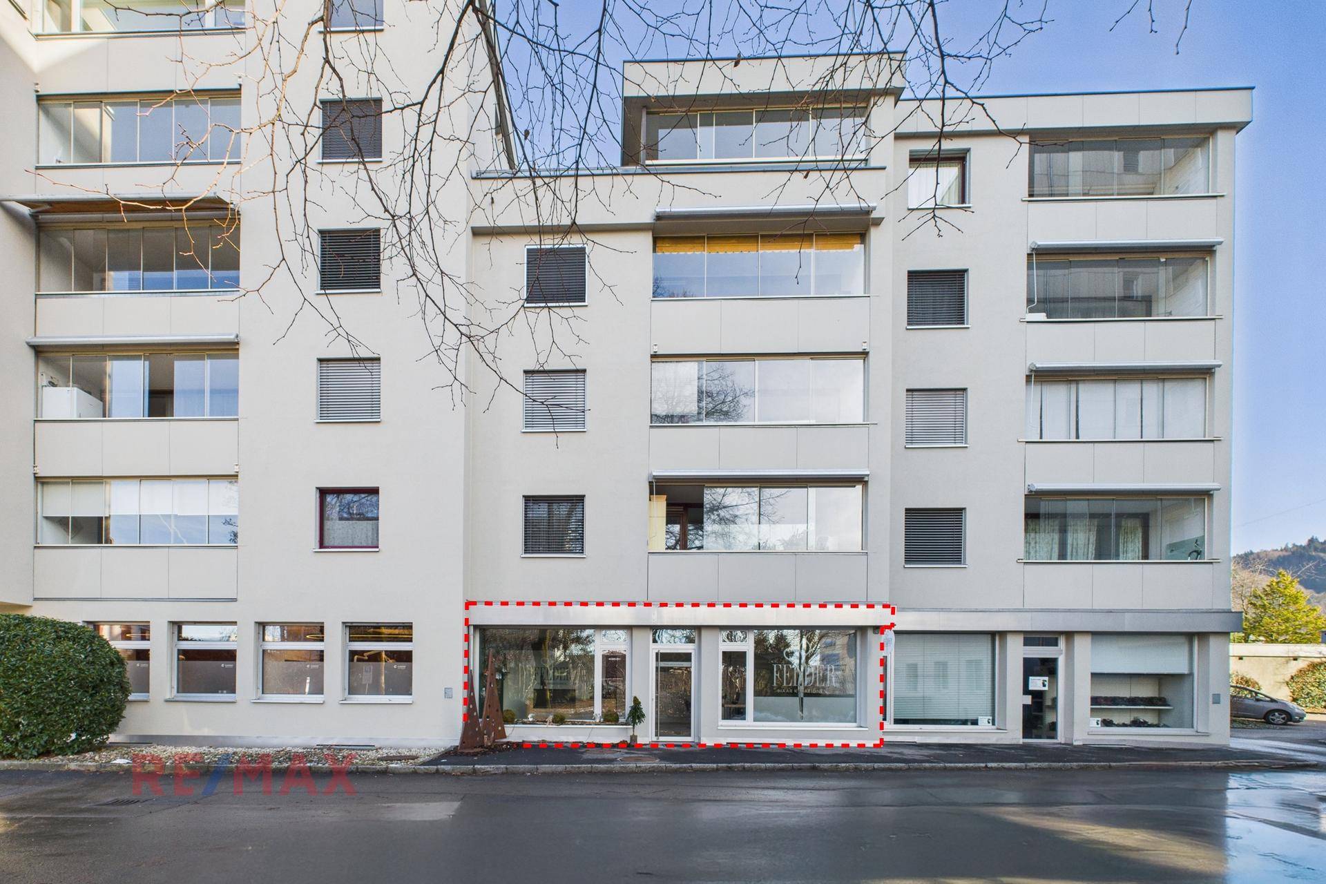 Gesamtansicht der Geschäftsfassade im Erdgeschoss eines Mehrfamilienhauses mit großen Fenstern.