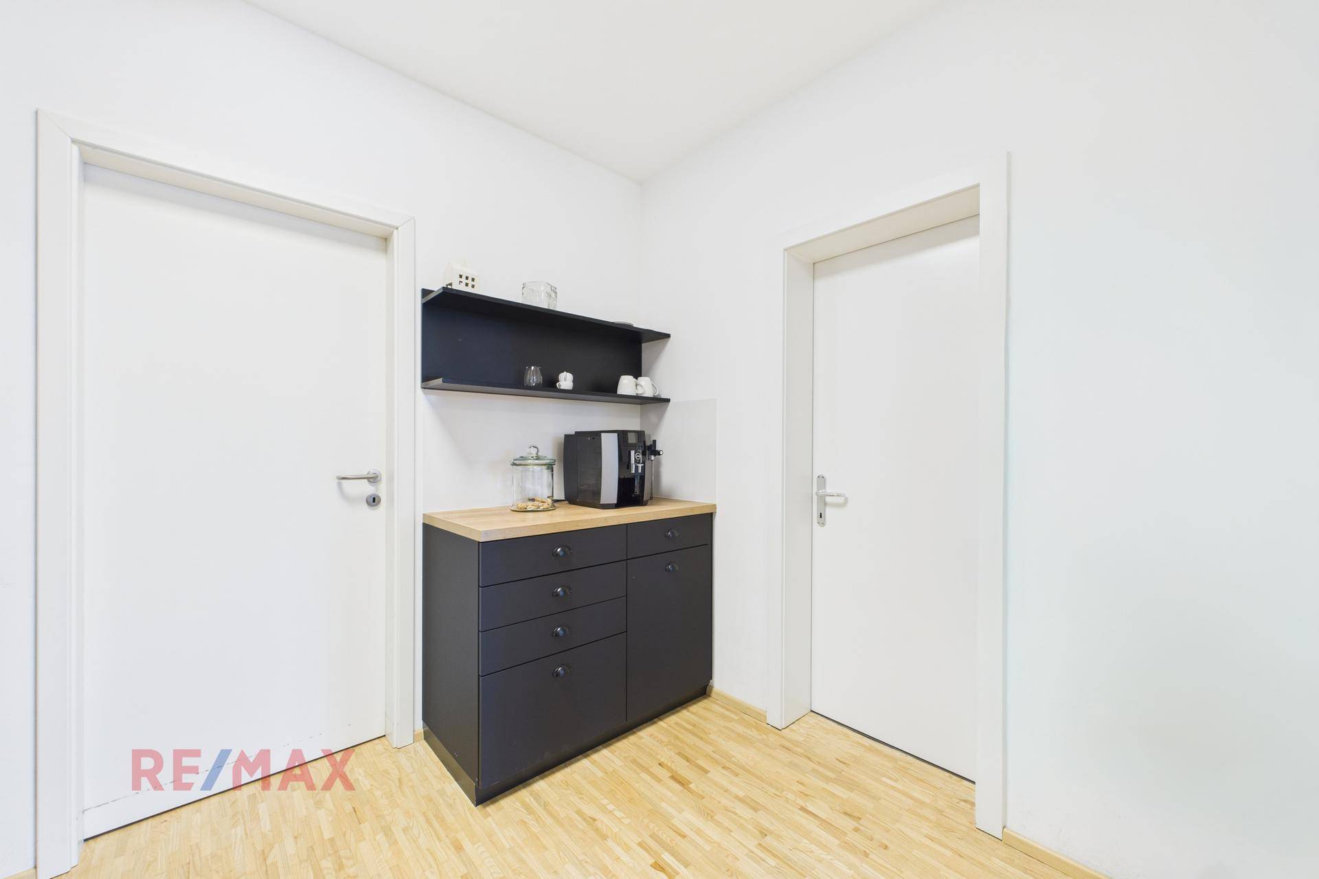 Heller Flur mit einem Sideboard, Kaffeemaschine und zwei Türen zu weiteren Räumen.