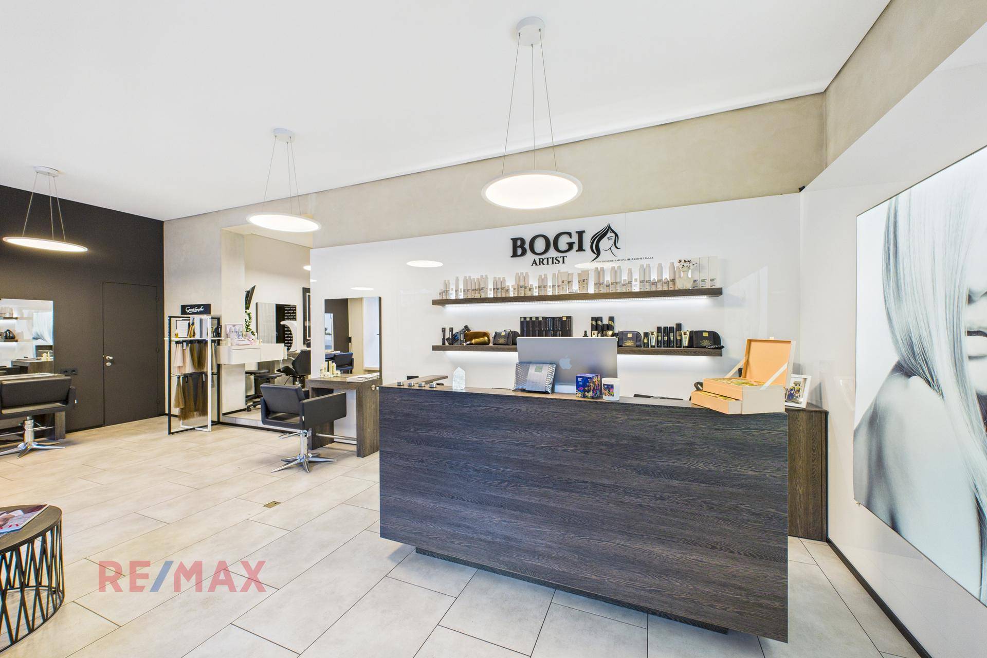 Moderner Empfangsbereich eines Salons mit dunklem Tresen und Produktpräsentation.